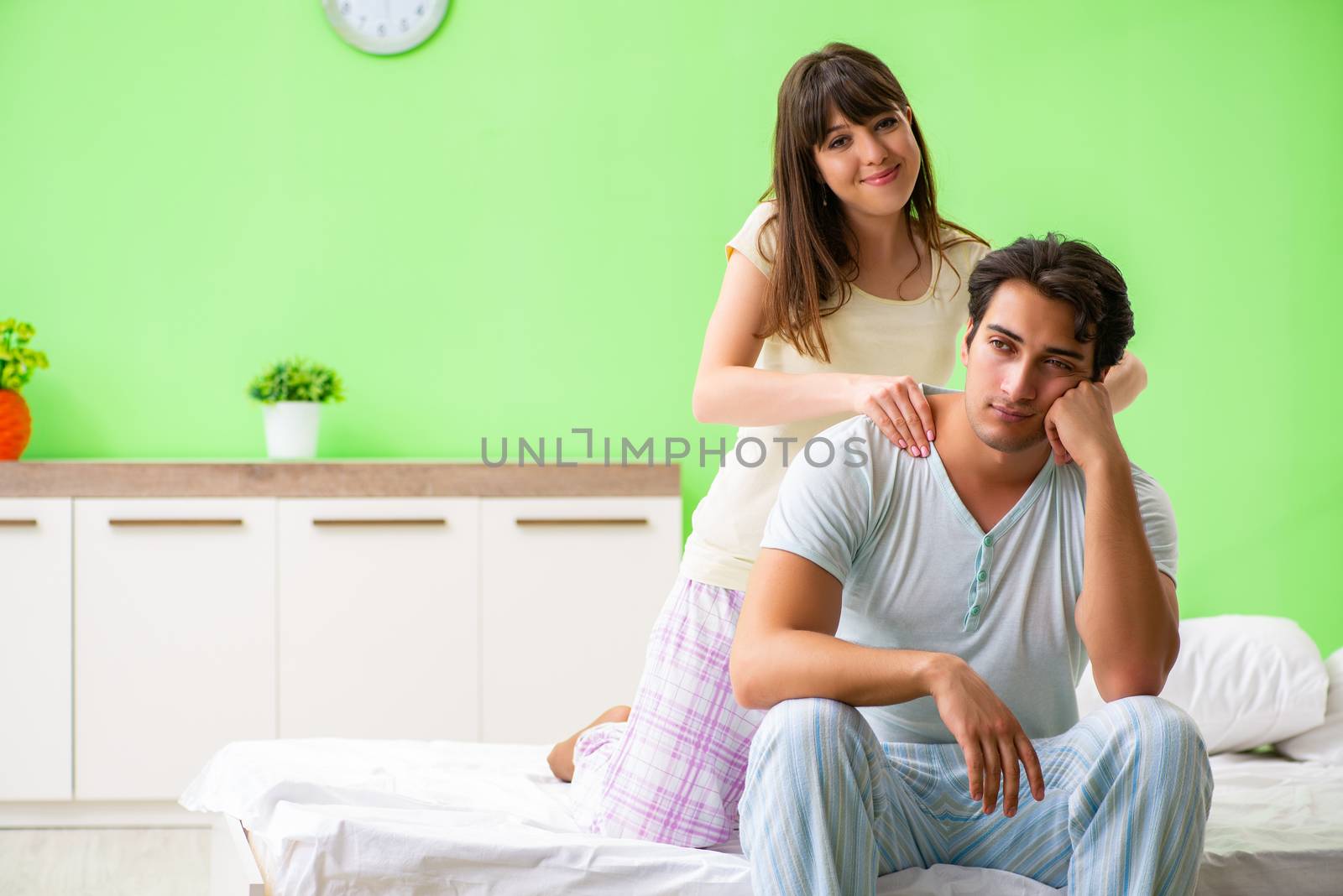 Woman doing massage to her husband in bedroom 