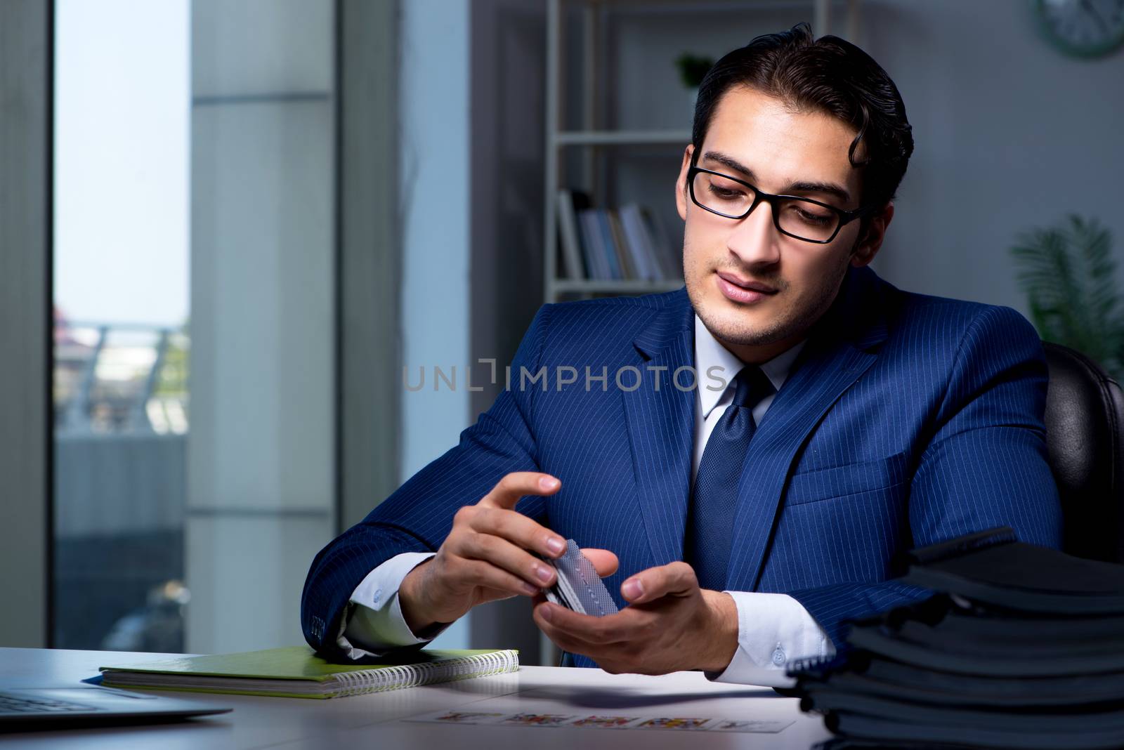 Young business playing cards late in office