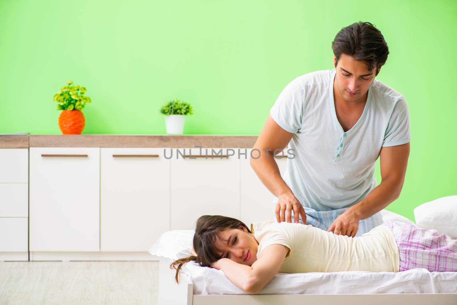 Man doing massage to his wife in bedroom 