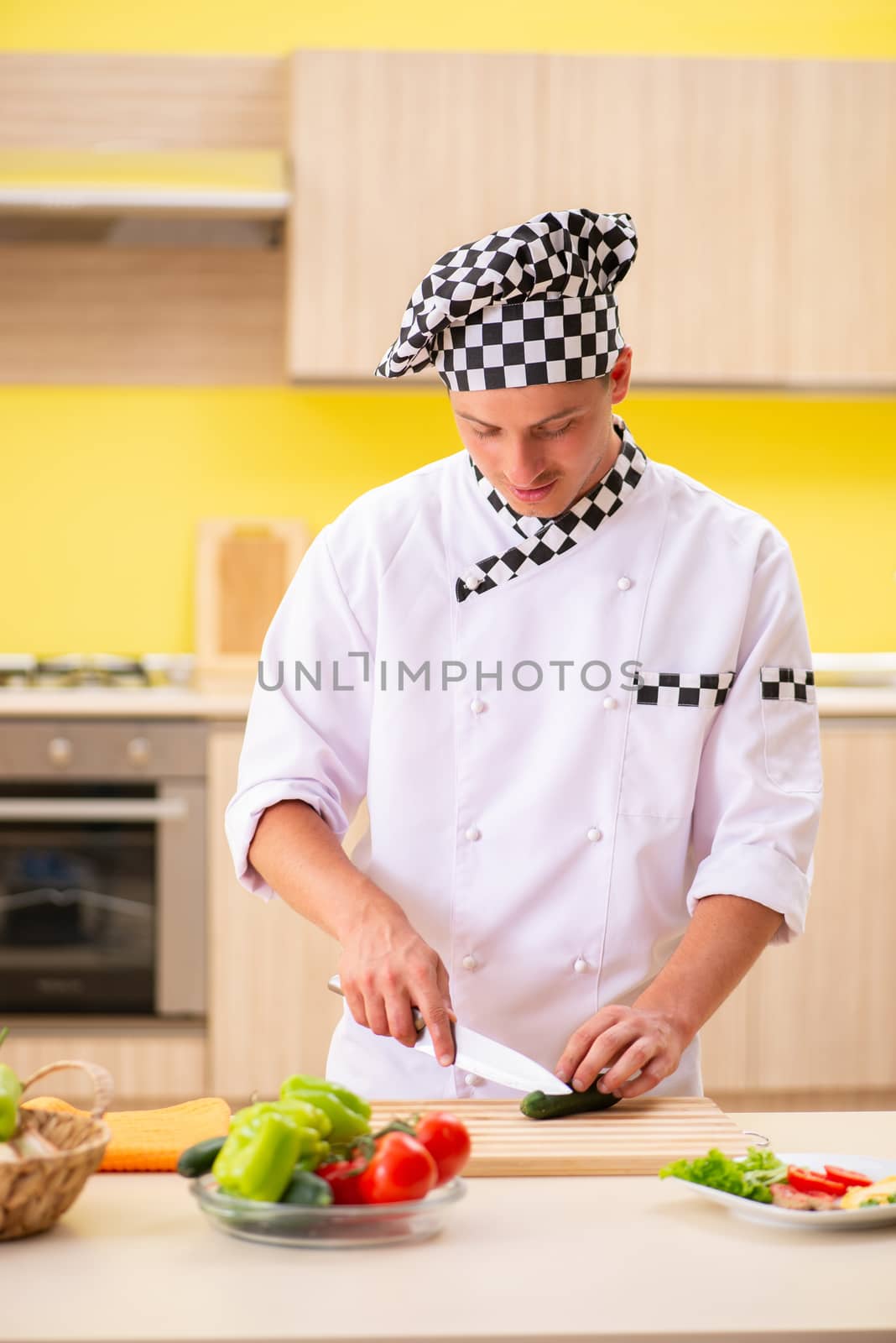 Young professional cook preparing salad at kitchen