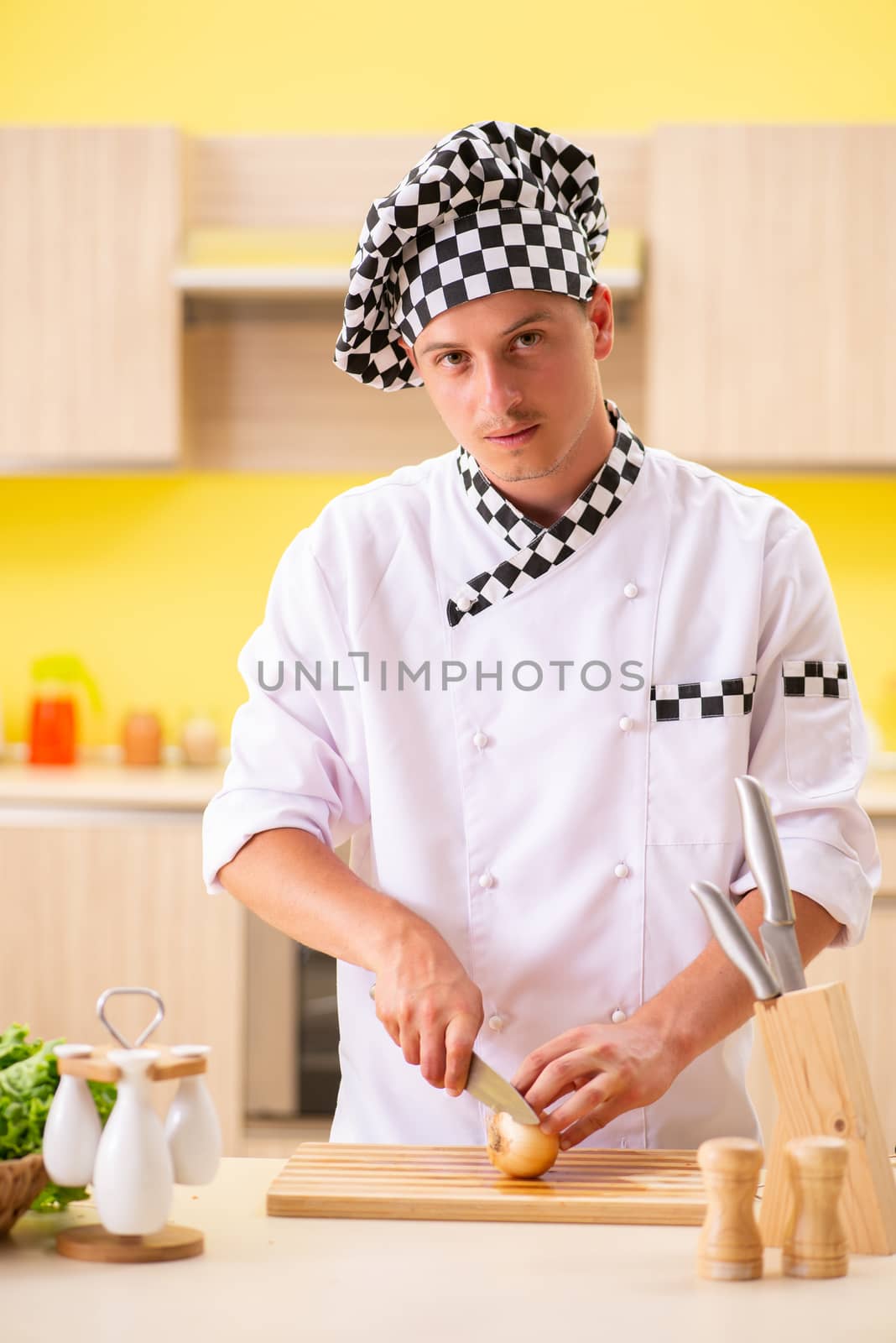 Young professional cook preparing salad at kitchen