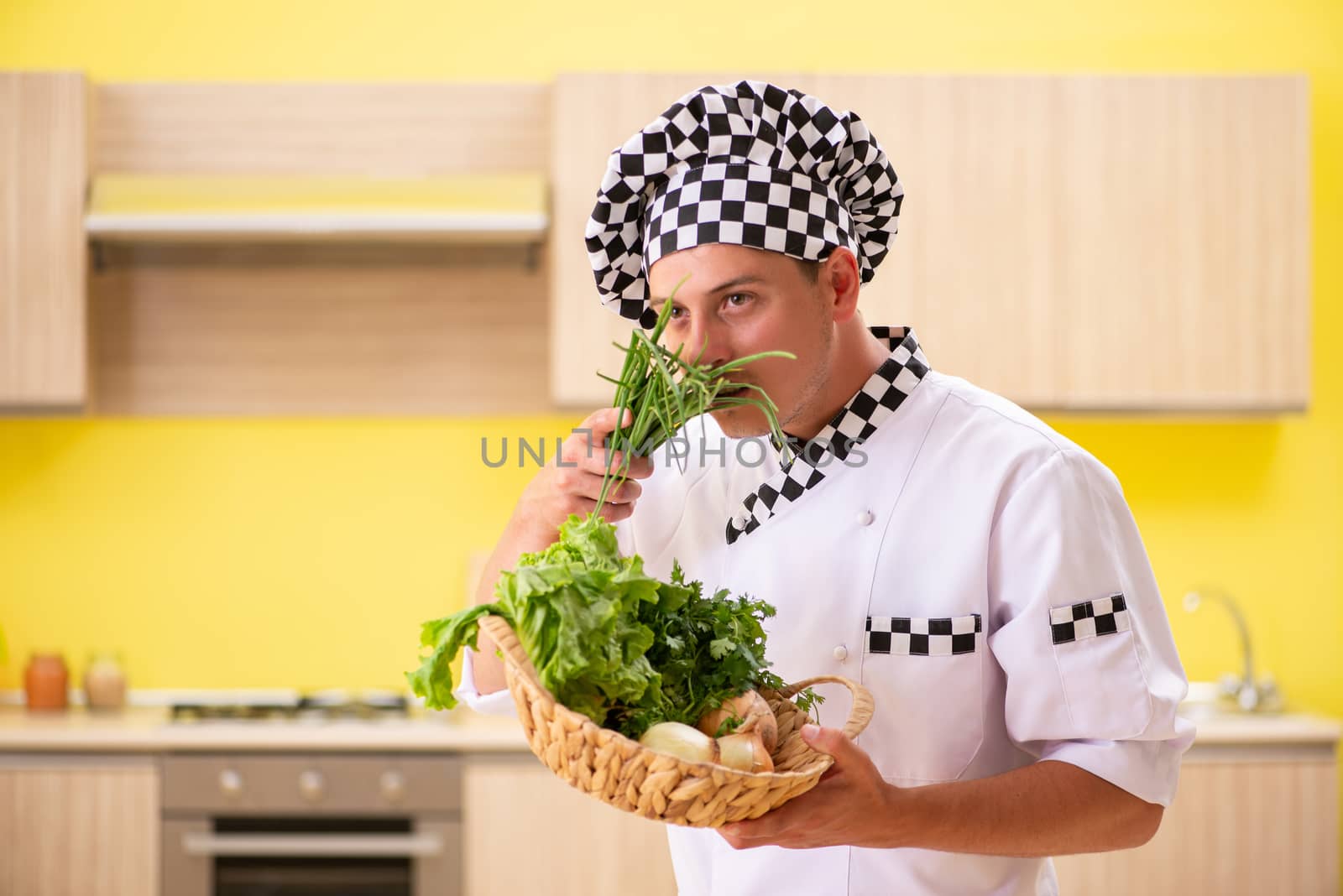 Young professional cook preparing salad at kitchen