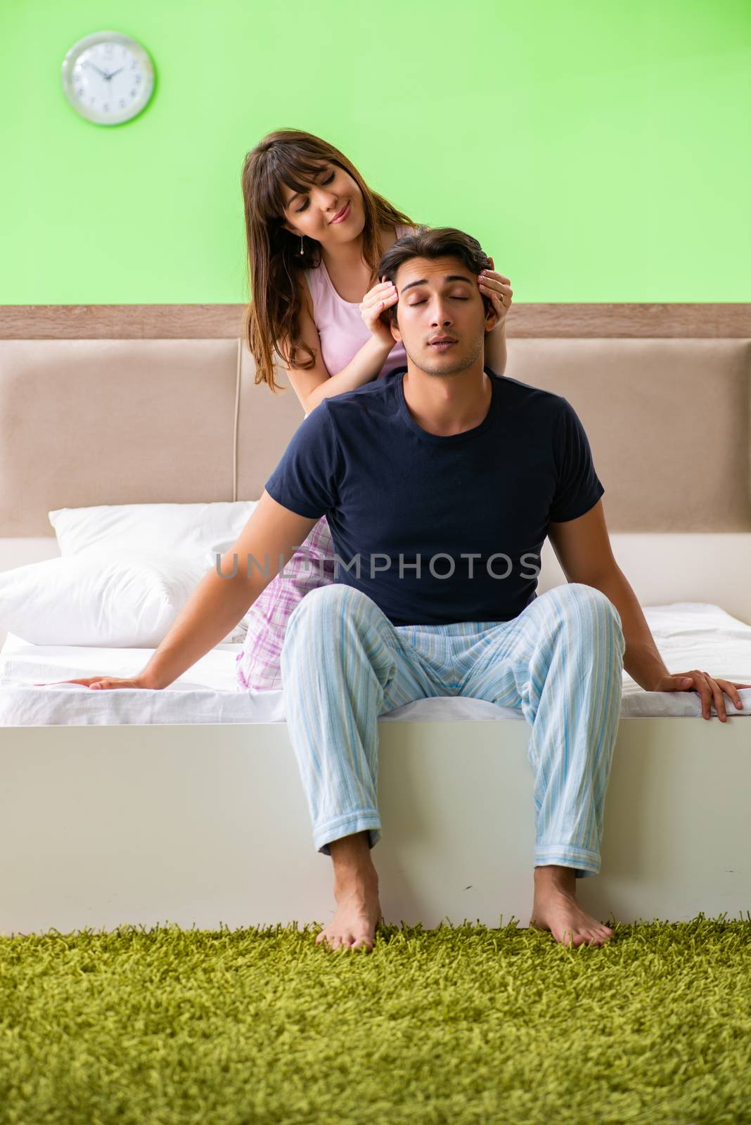 Woman doing massage to her husband in bedroom 