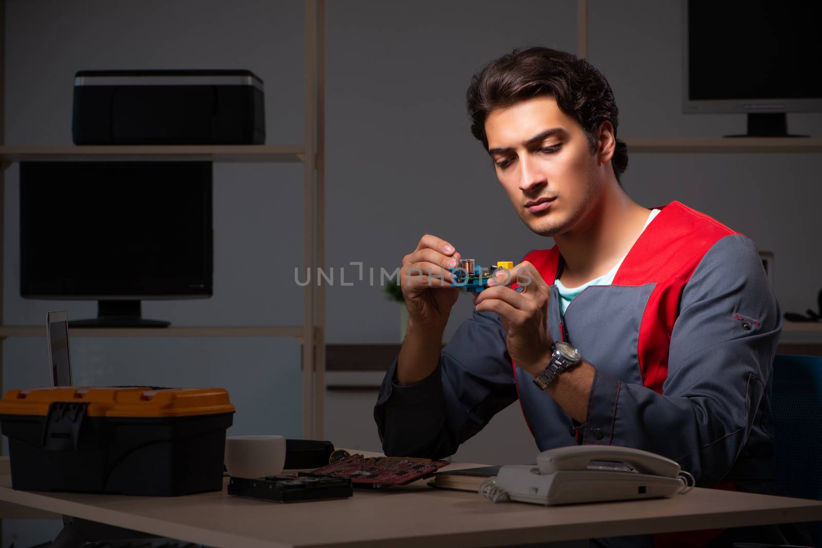 Young handsome repairman repairing computer 