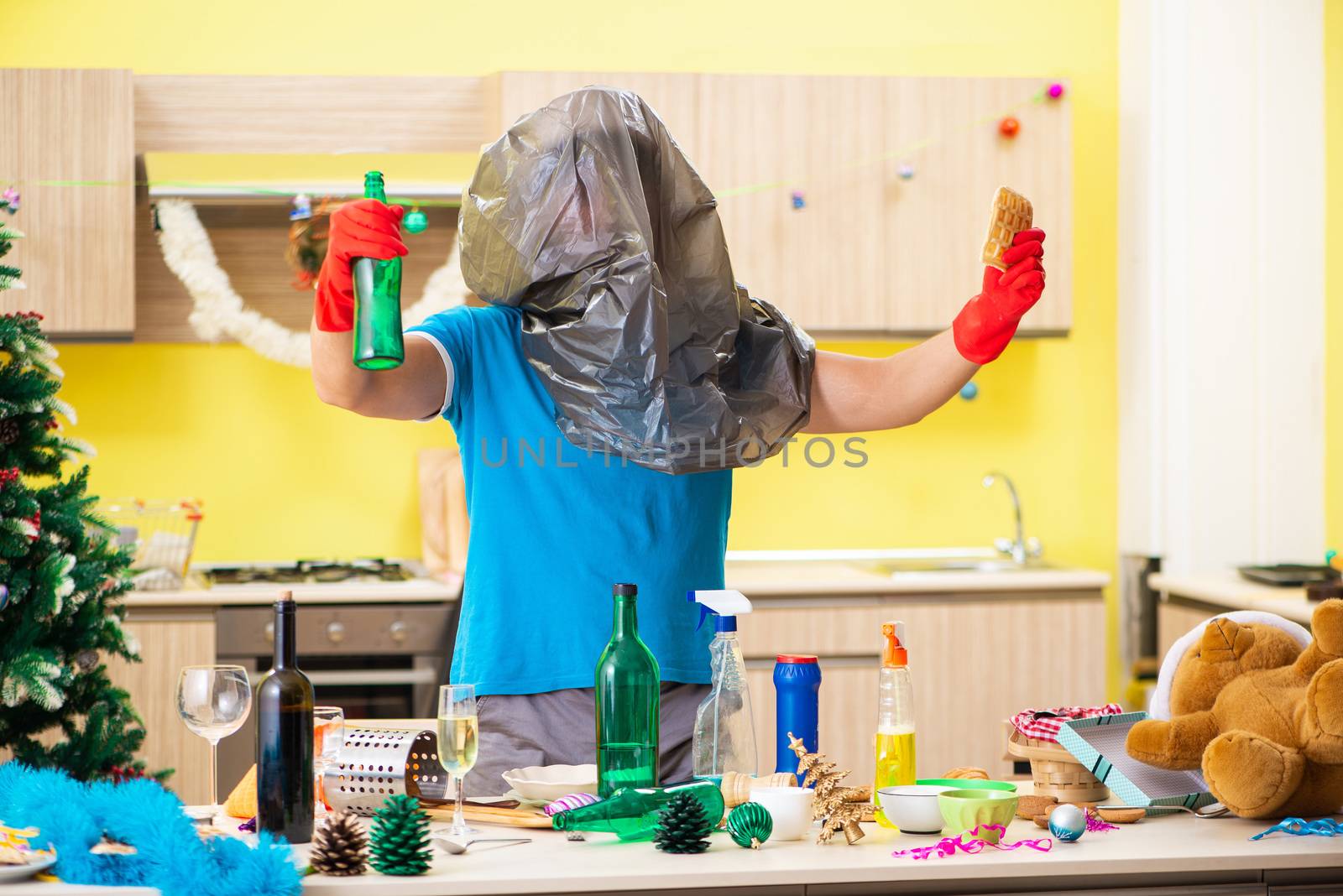 Young man cleaning kitchen after Christmas party 