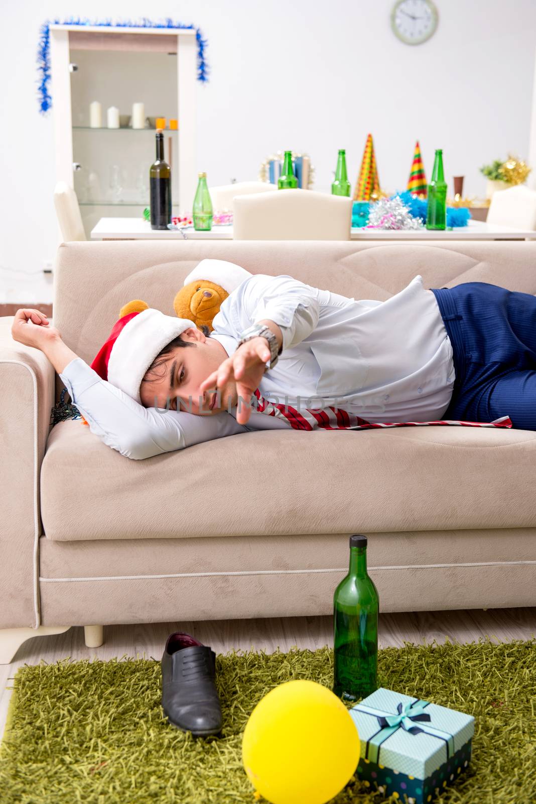 Young handsome employee celebrating Christmas at workplace 