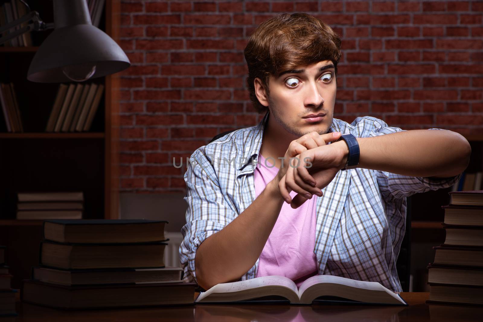Young handsome student preparing for exams at night 