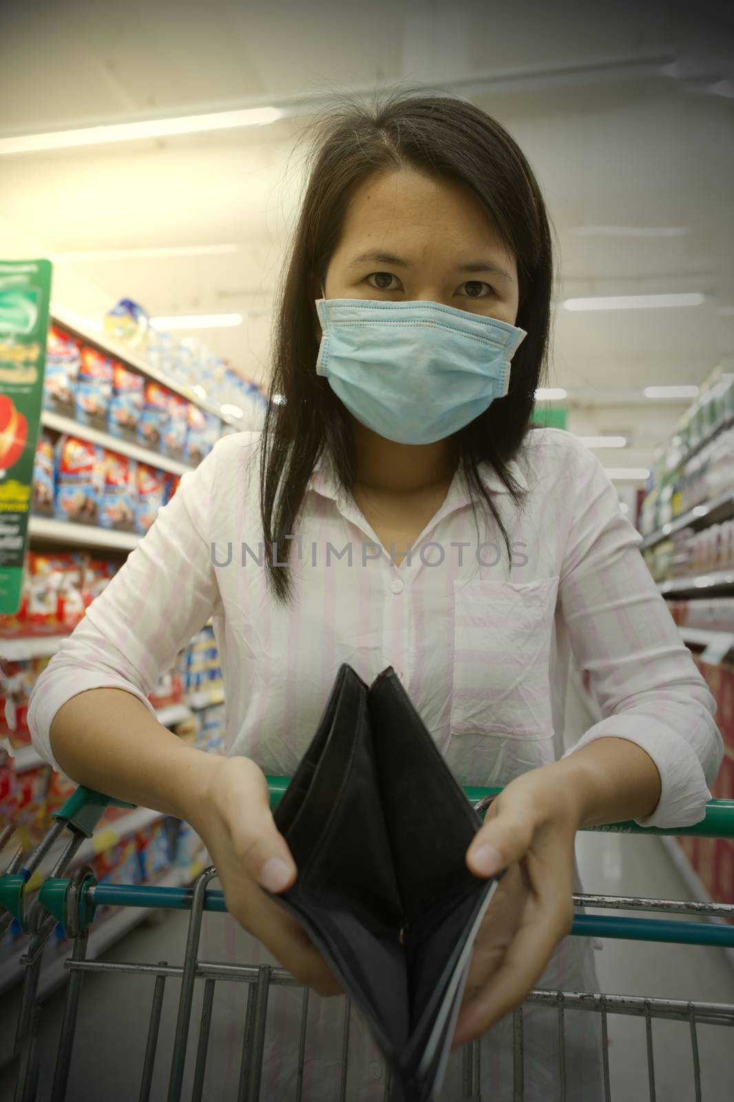 A woman shopping in a mall shows a wallet wearing a mask against the coronavirus select focus.