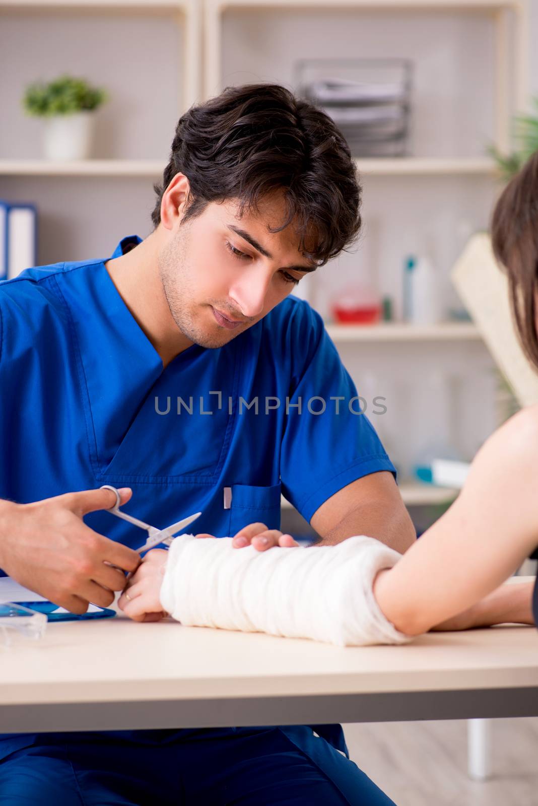 Young woman with bandaged arm visiting male doctor traumotologist 