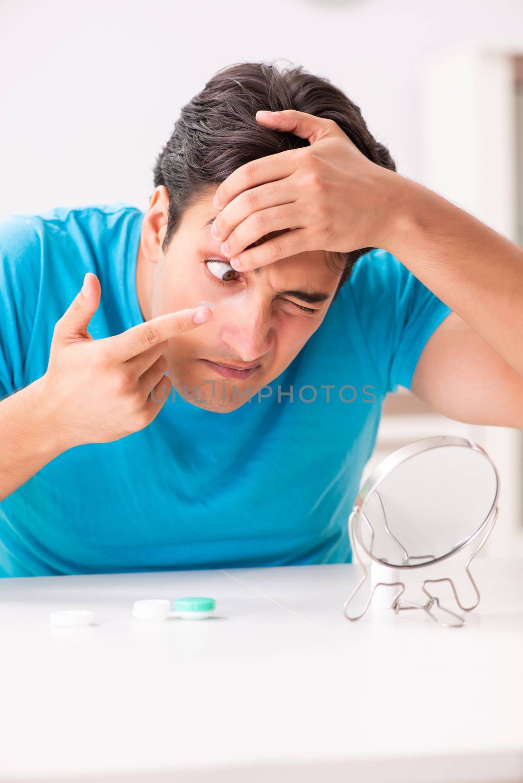 Man trying contact lenses at home