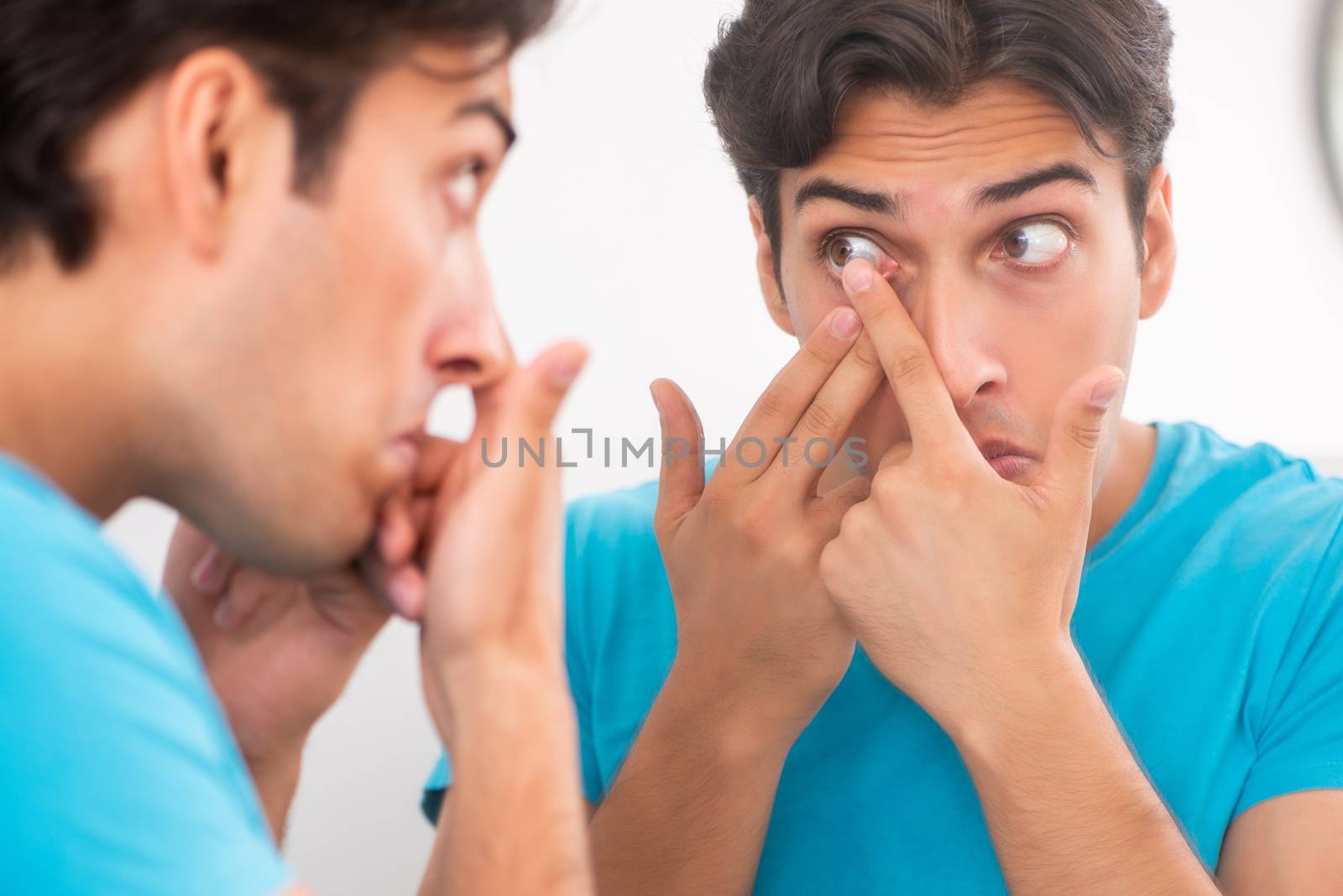 Man trying contact lenses at home by Elnur