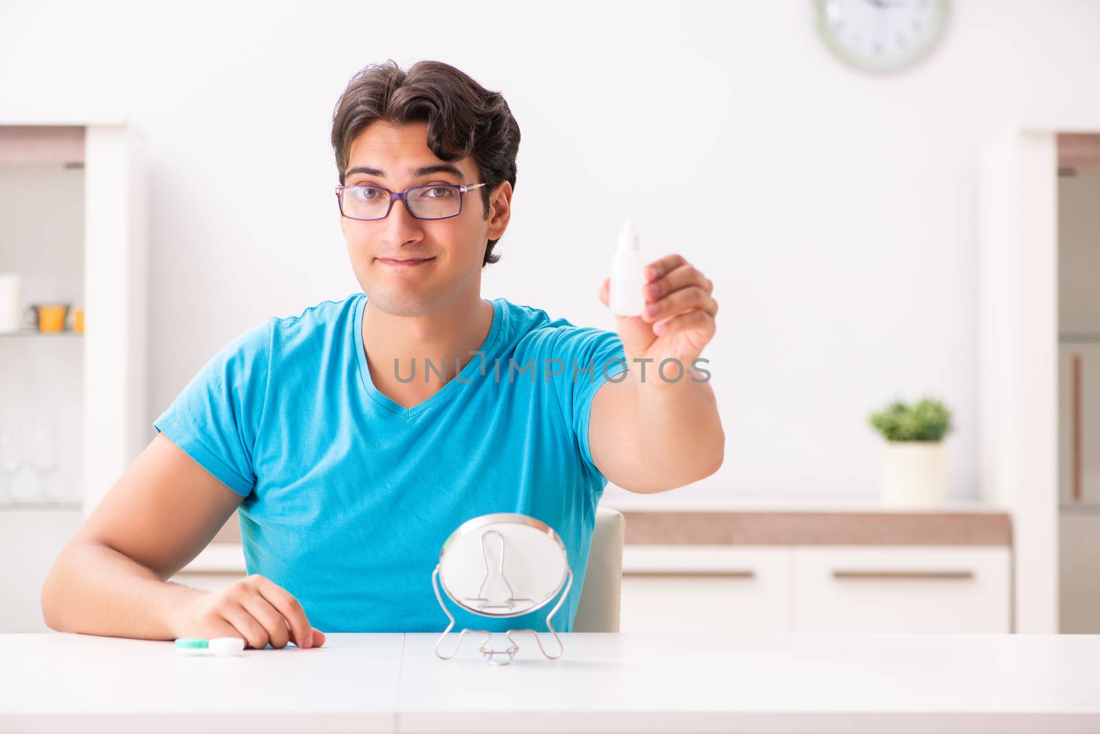 Man trying contact lenses at home