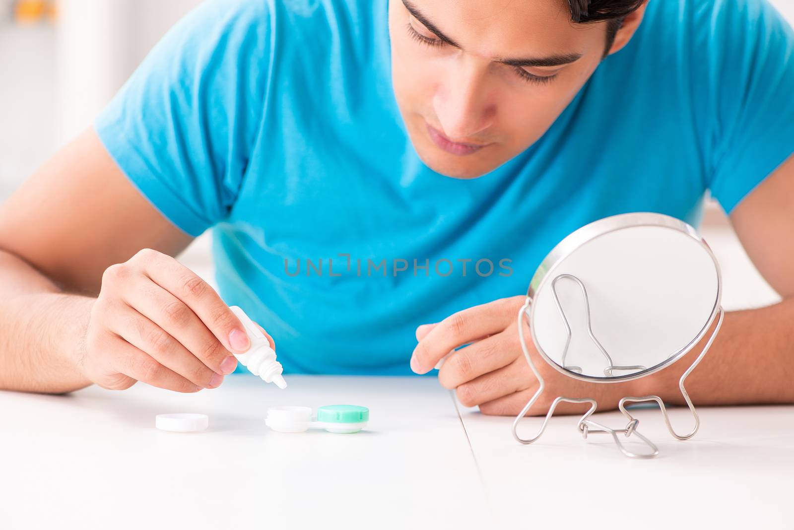 Man trying contact lenses at home by Elnur