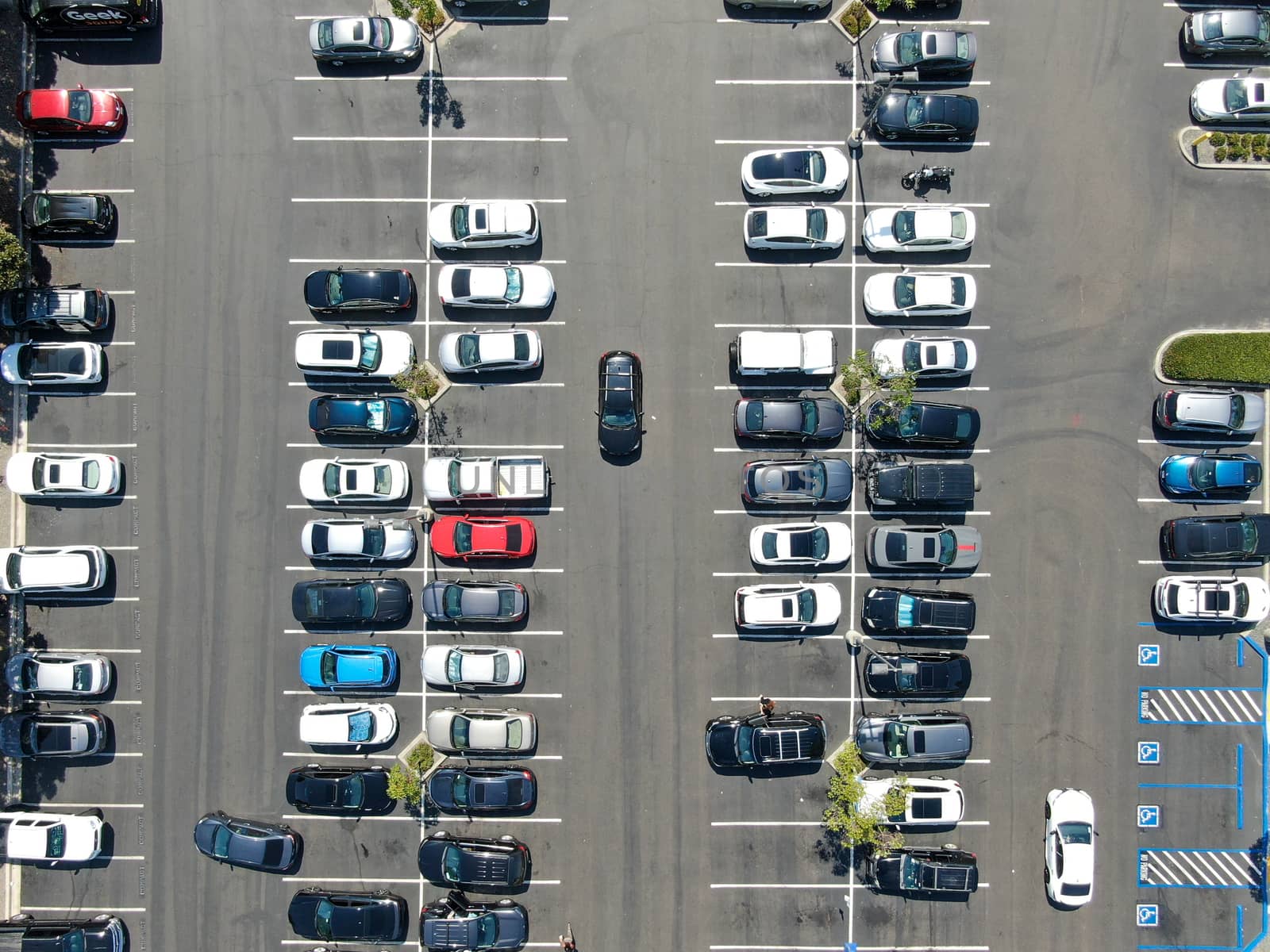 Aerial top view of parking lot at shopping mall with varieties of colored vehicles. by Bonandbon