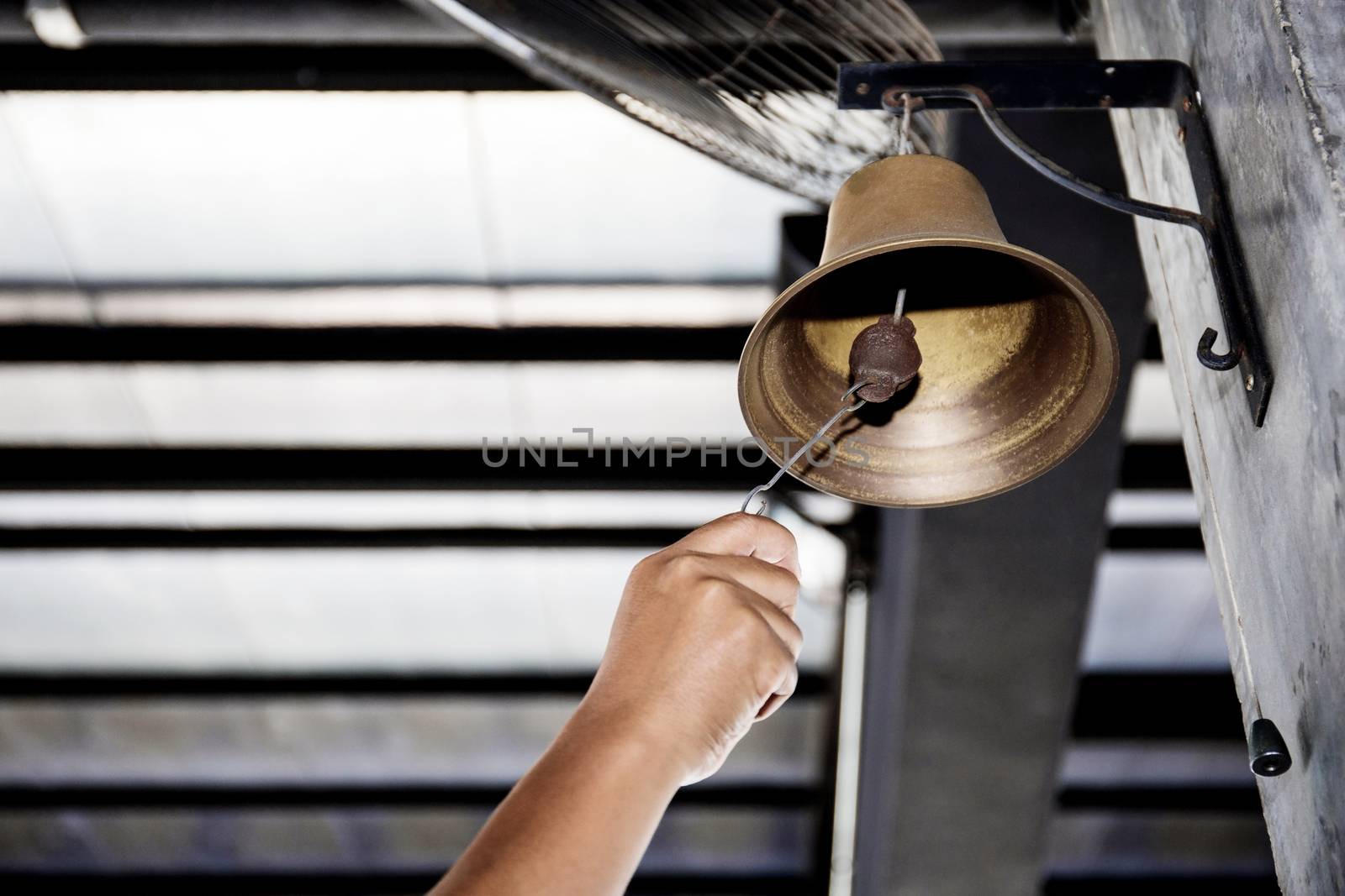 Hand is shaking bell hanging on pole of the boxing stadium.