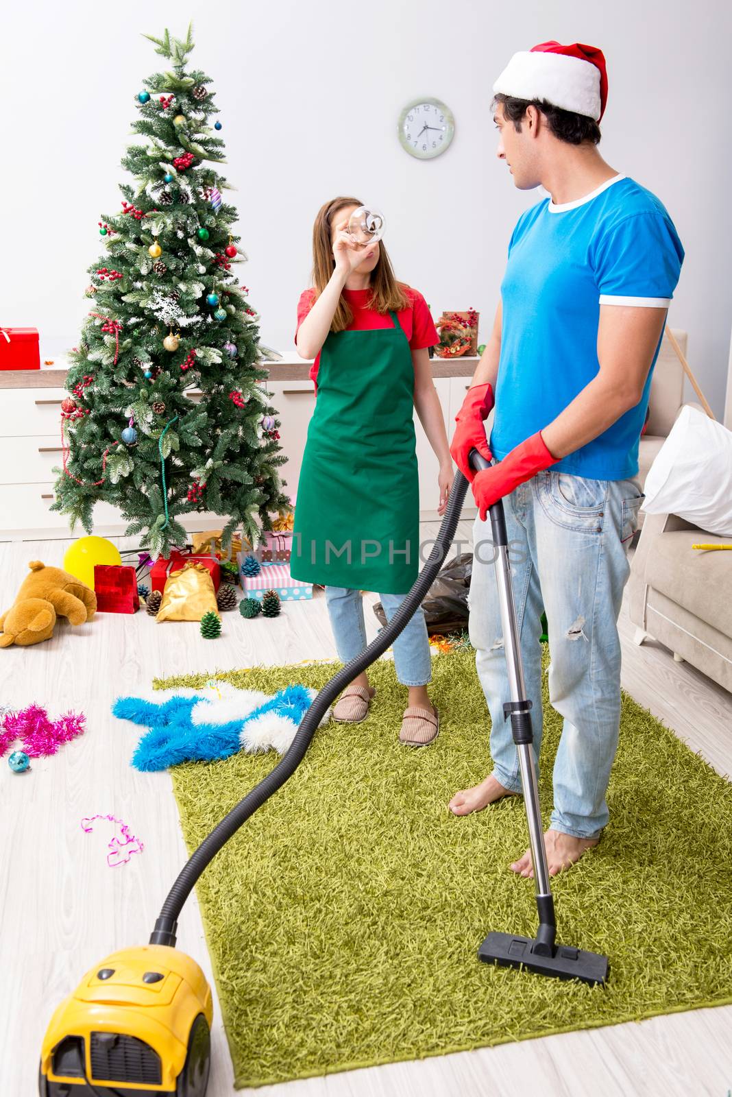 Young family cleaning apartment after christmas party by Elnur