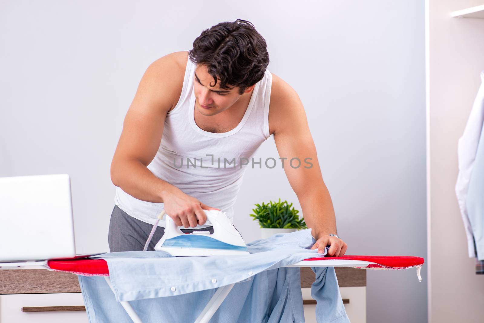 Young man freelancer ironing in the bedroom 