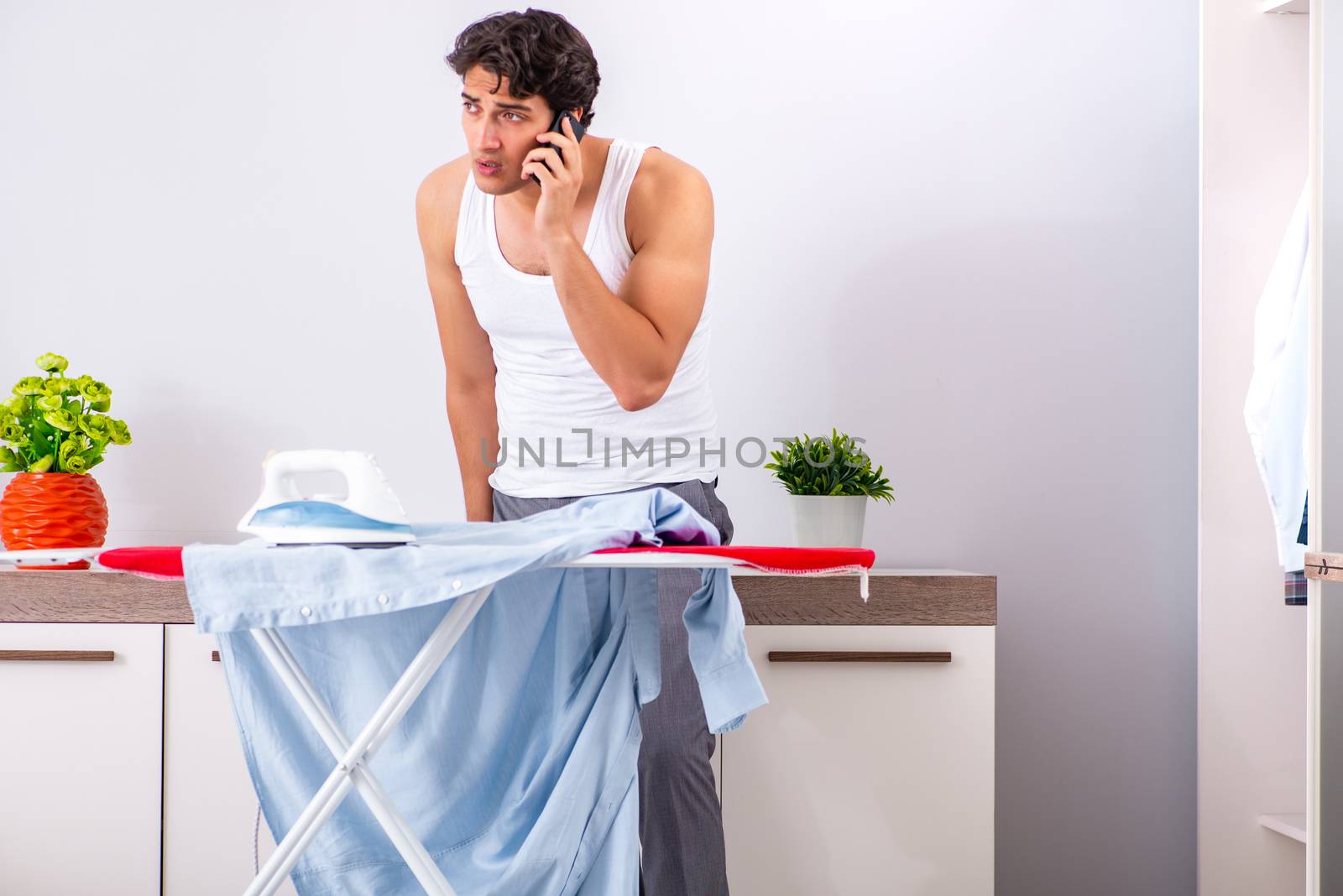 Young man ironing in the bedroom 