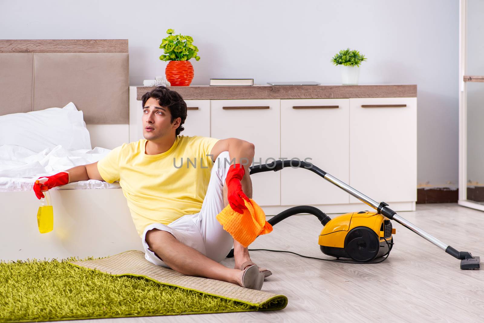 Young handsome man cleaning in the bedroom