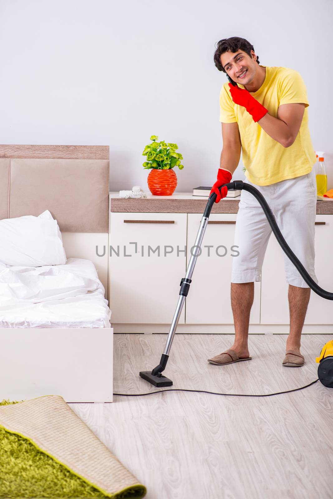 Young handsome man cleaning in the bedroom by Elnur