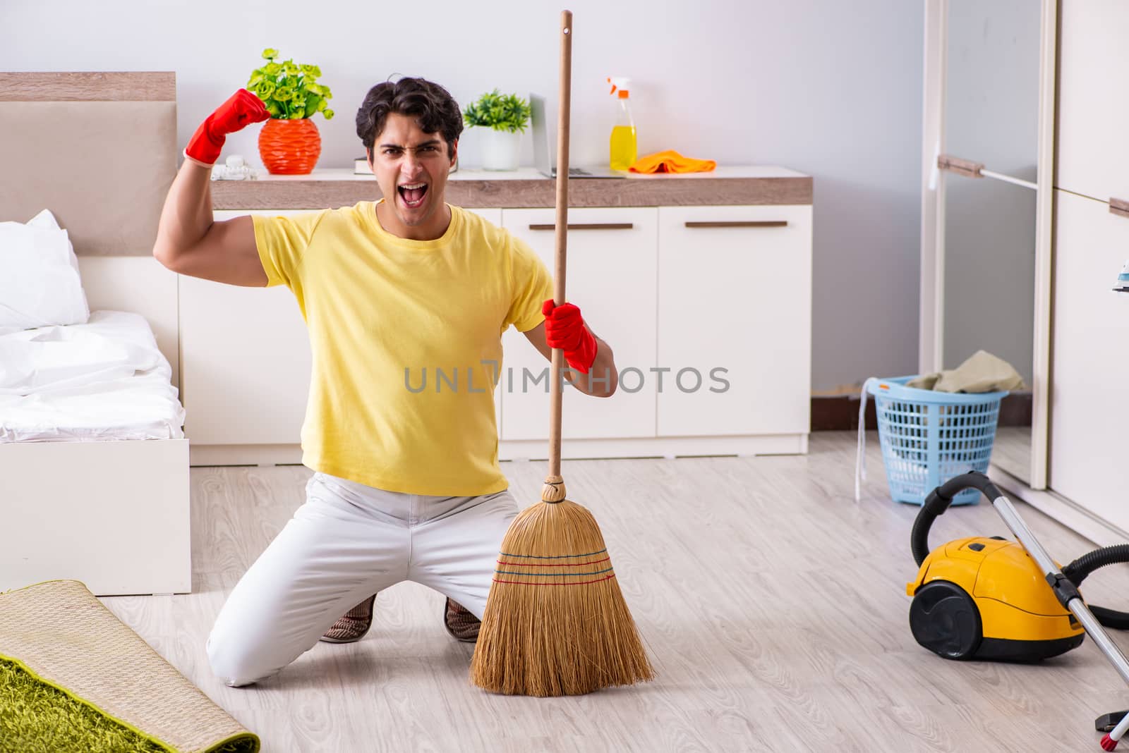 Young handsome man cleaning in the bedroom