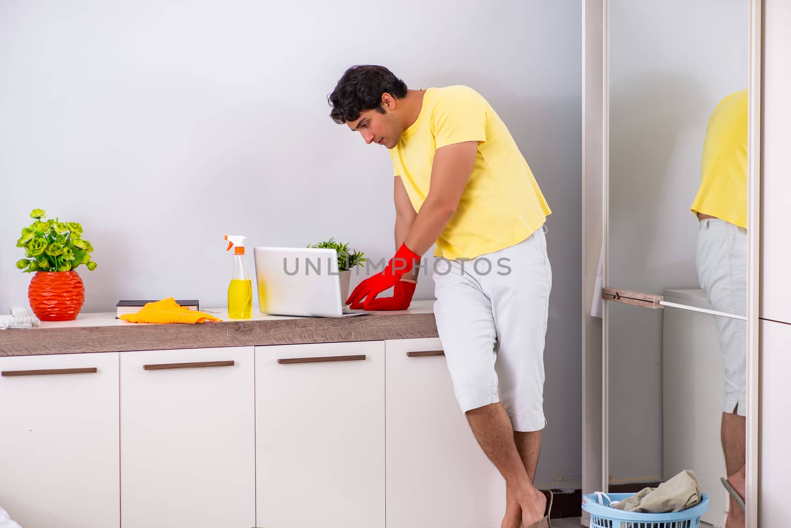 Young handsome man cleaning in the bedroom