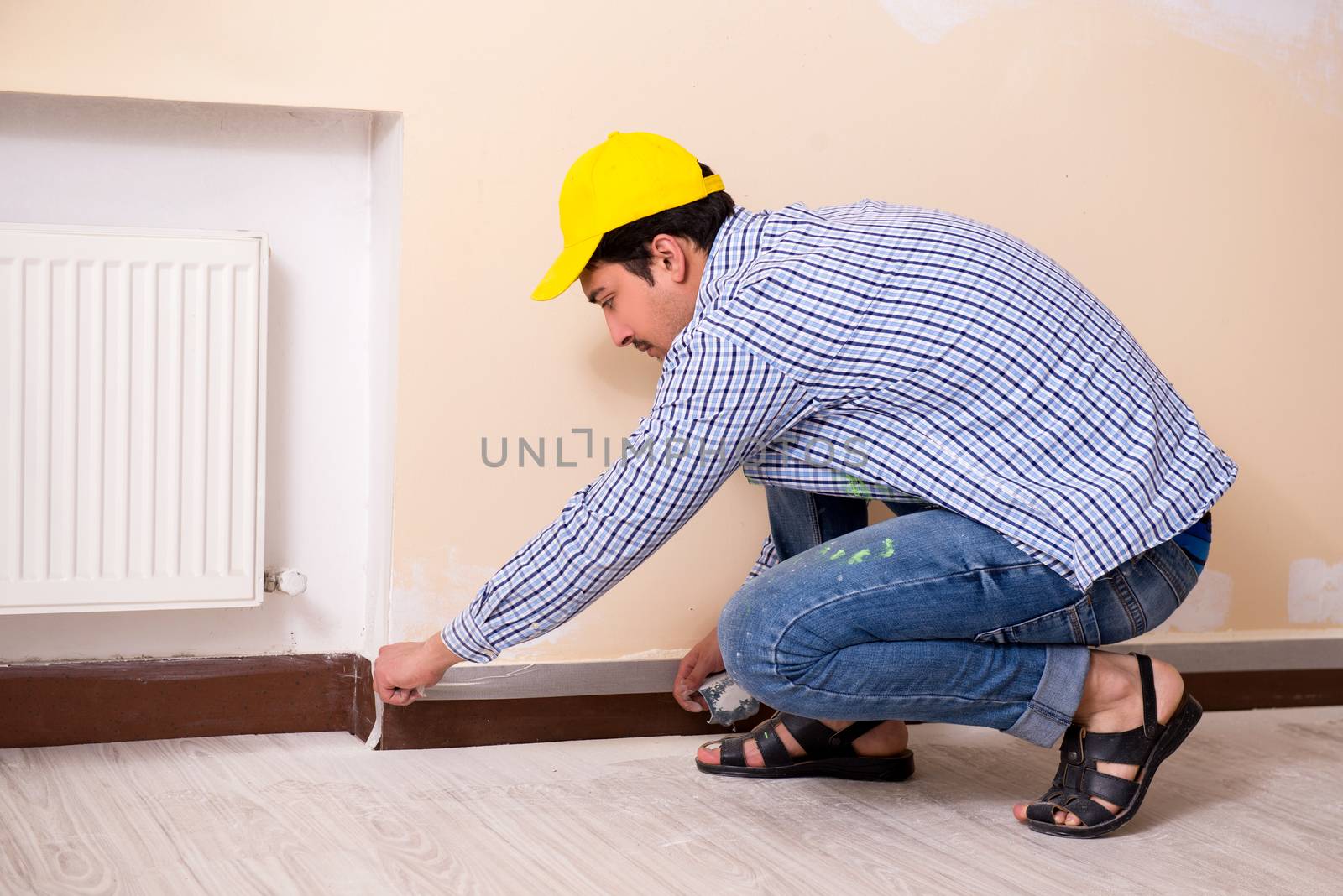 Young contractor sanding wall down with sandpaper 