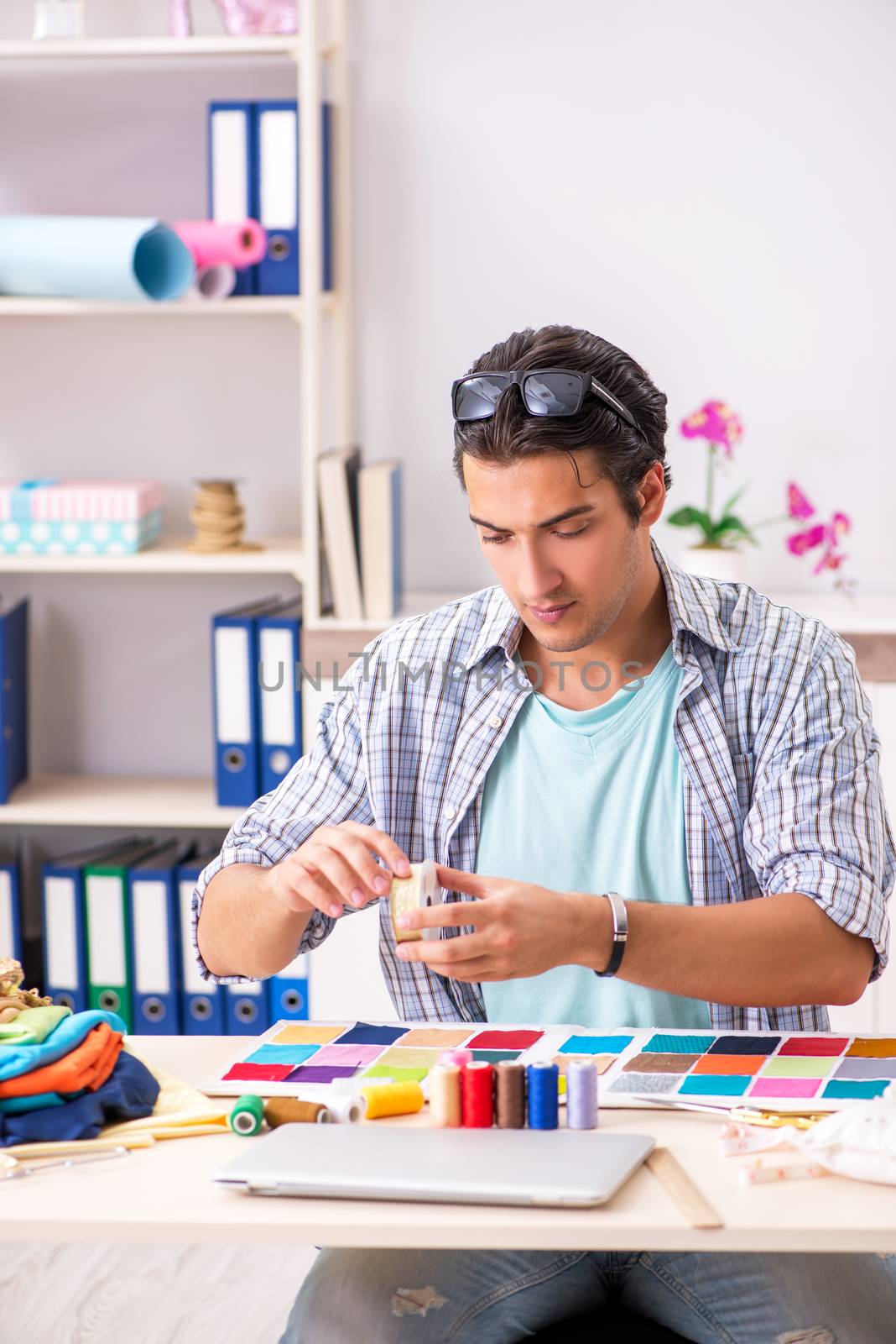 Young handsome tailor working in his workshop