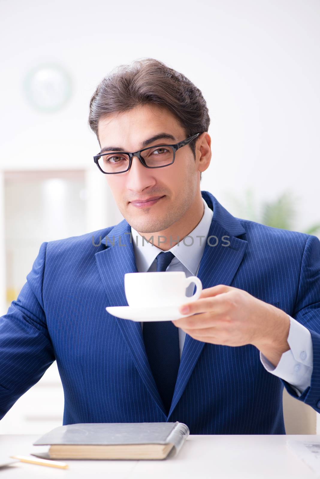 Young handsome businessman drinking coffee in the office  by Elnur