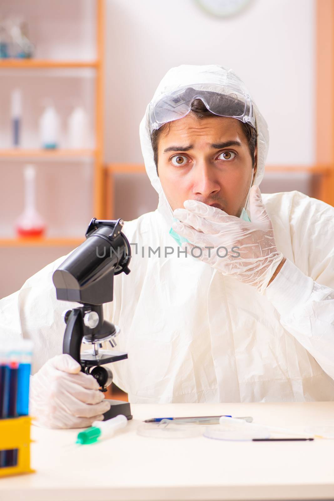 Young biochemist wearing protective suit working in the lab by Elnur