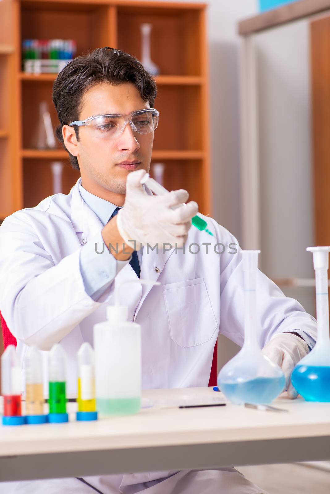 Young handsome biochemist working in the lab  by Elnur