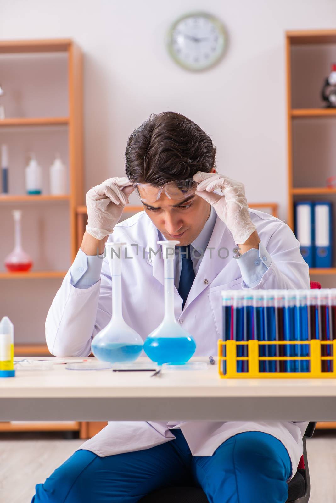 Young handsome biochemist working in the lab  by Elnur