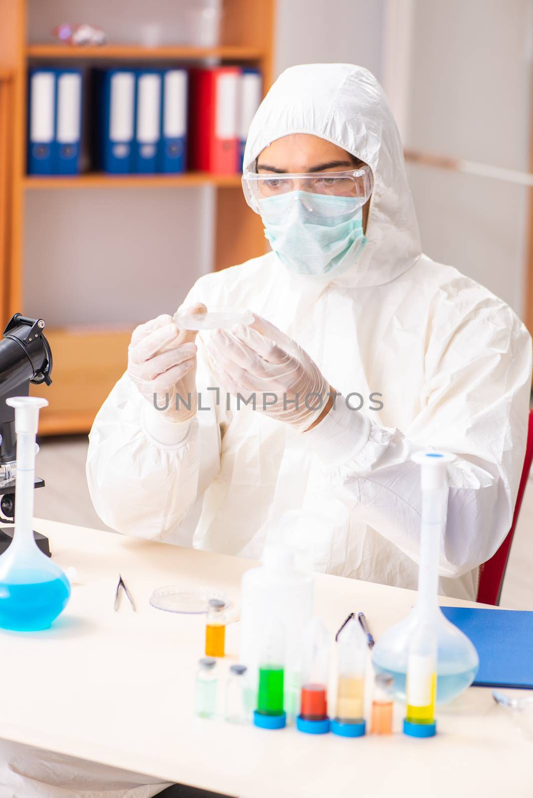 Young biochemist wearing protective suit working in the lab by Elnur