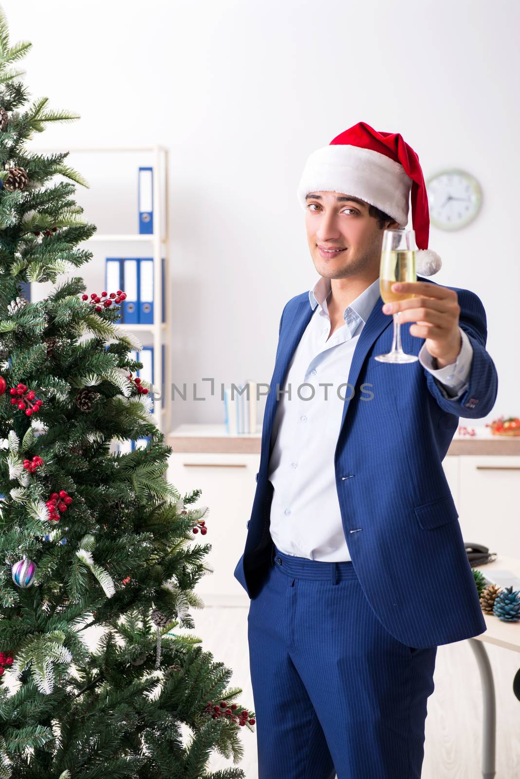 Young employee celebrating christmas at workplace by Elnur