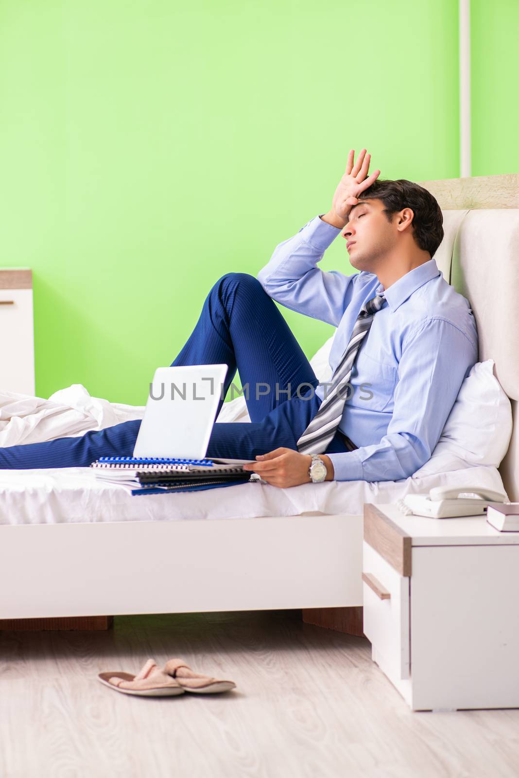 Businessman working overtime in hotel room by Elnur