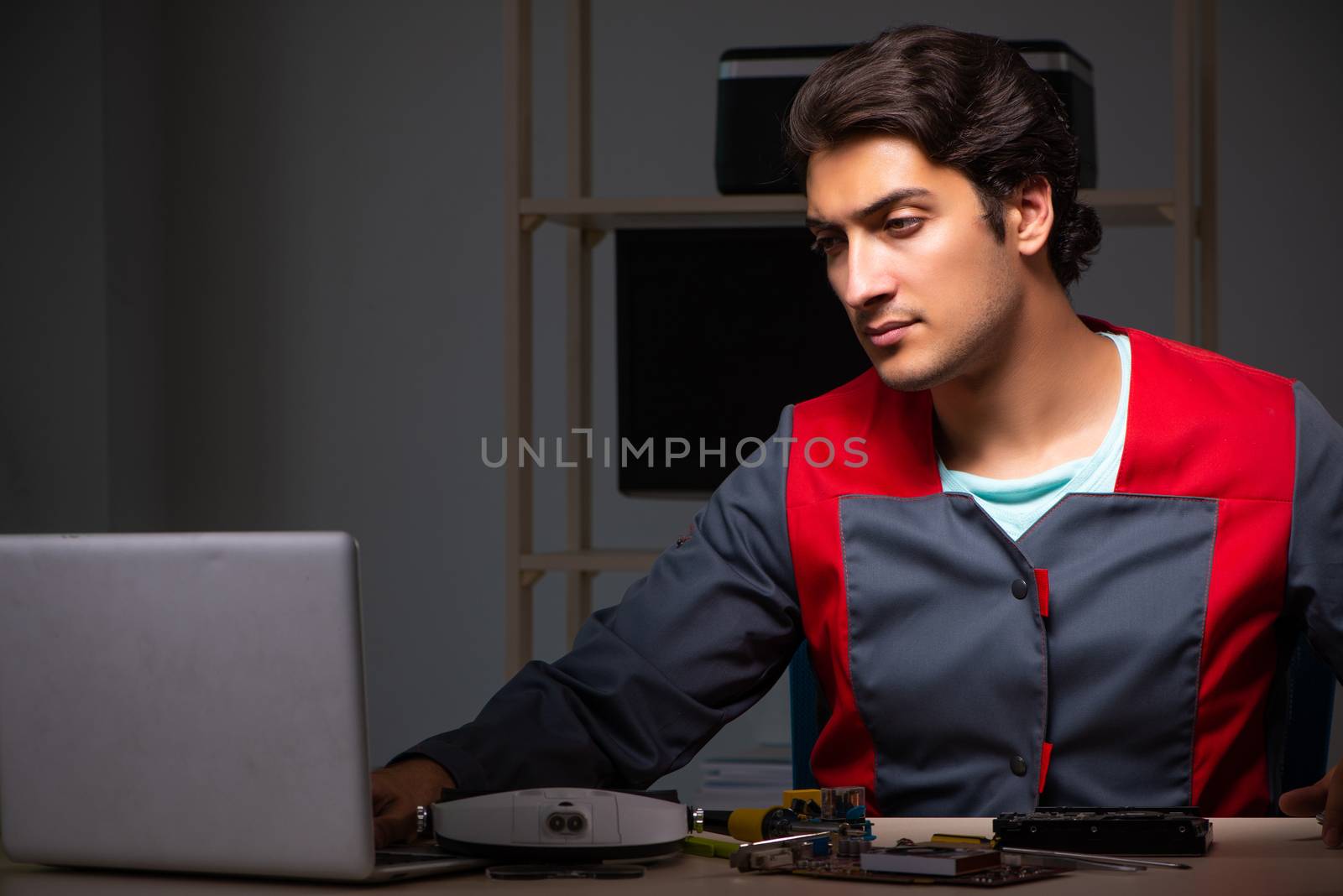 Young handsome repairman repairing computer 