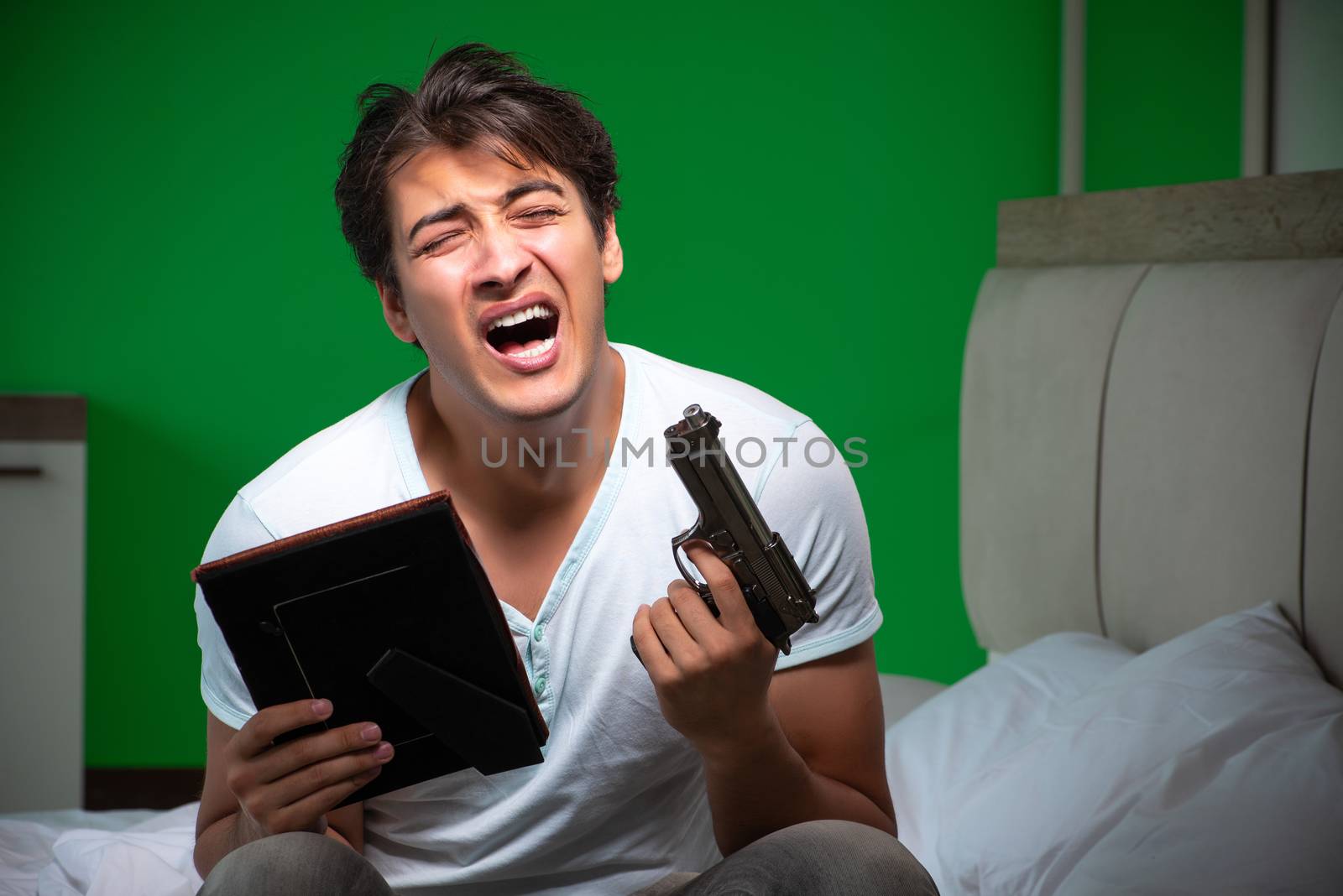 Young handsome man suffering from unrequited love in the bedroom 