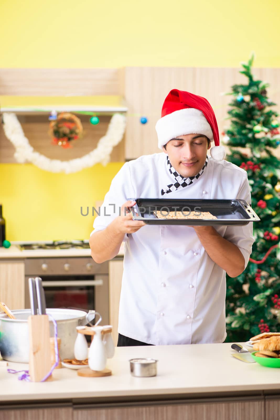 Young chef husband working in kitchen at Christmas eve  by Elnur