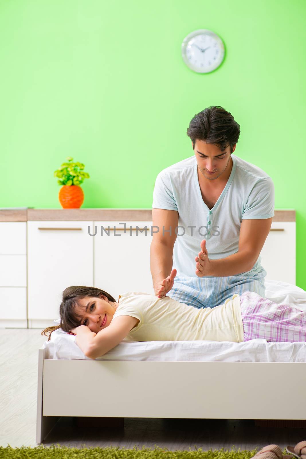 Man doing massage to his wife in bedroom 