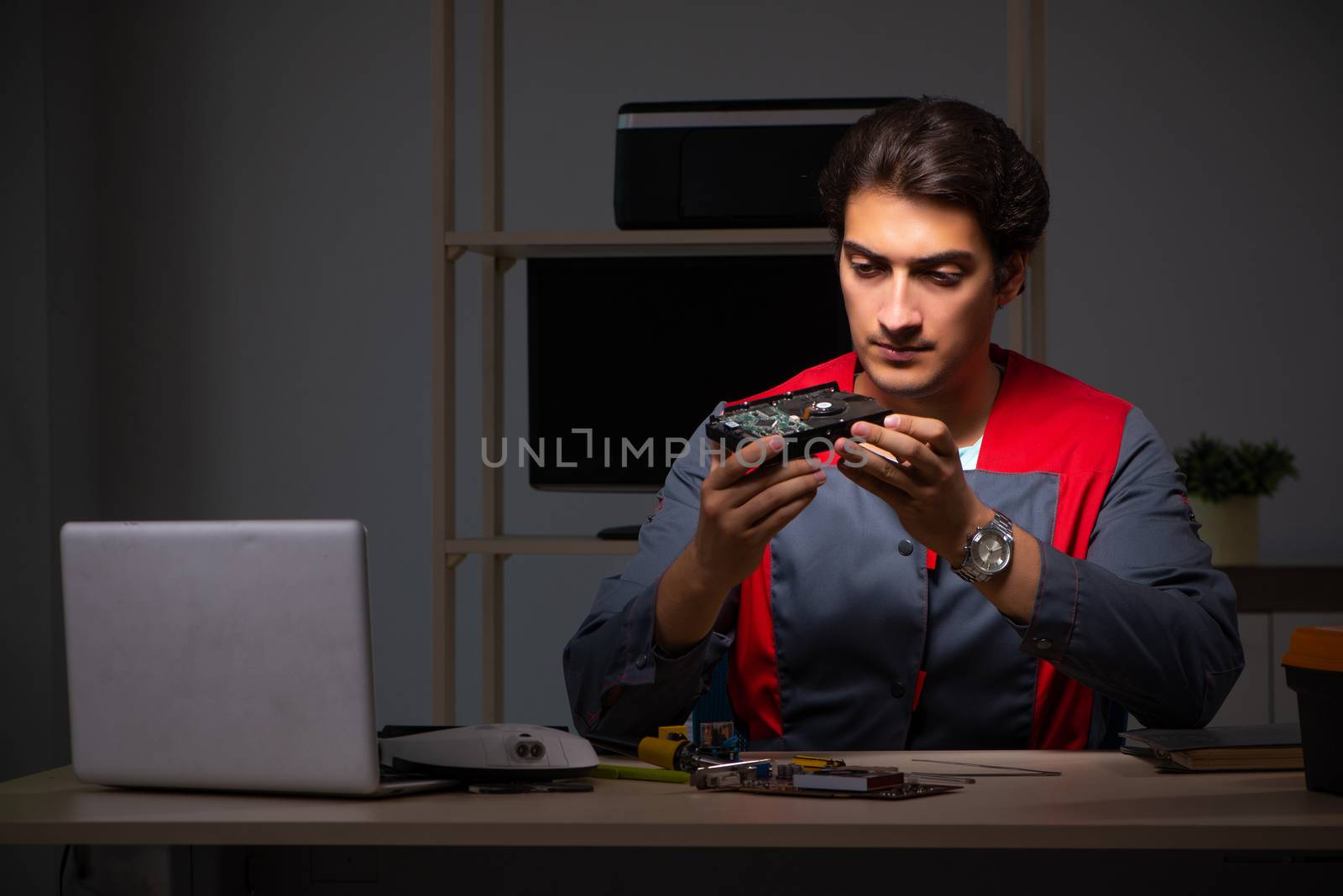 Young handsome repairman repairing computer 