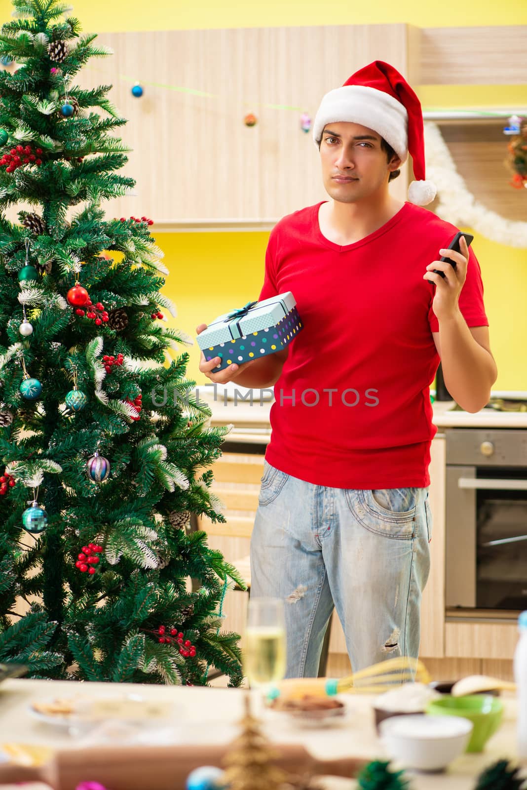 Young man celebrating Christmas in kitchen  by Elnur