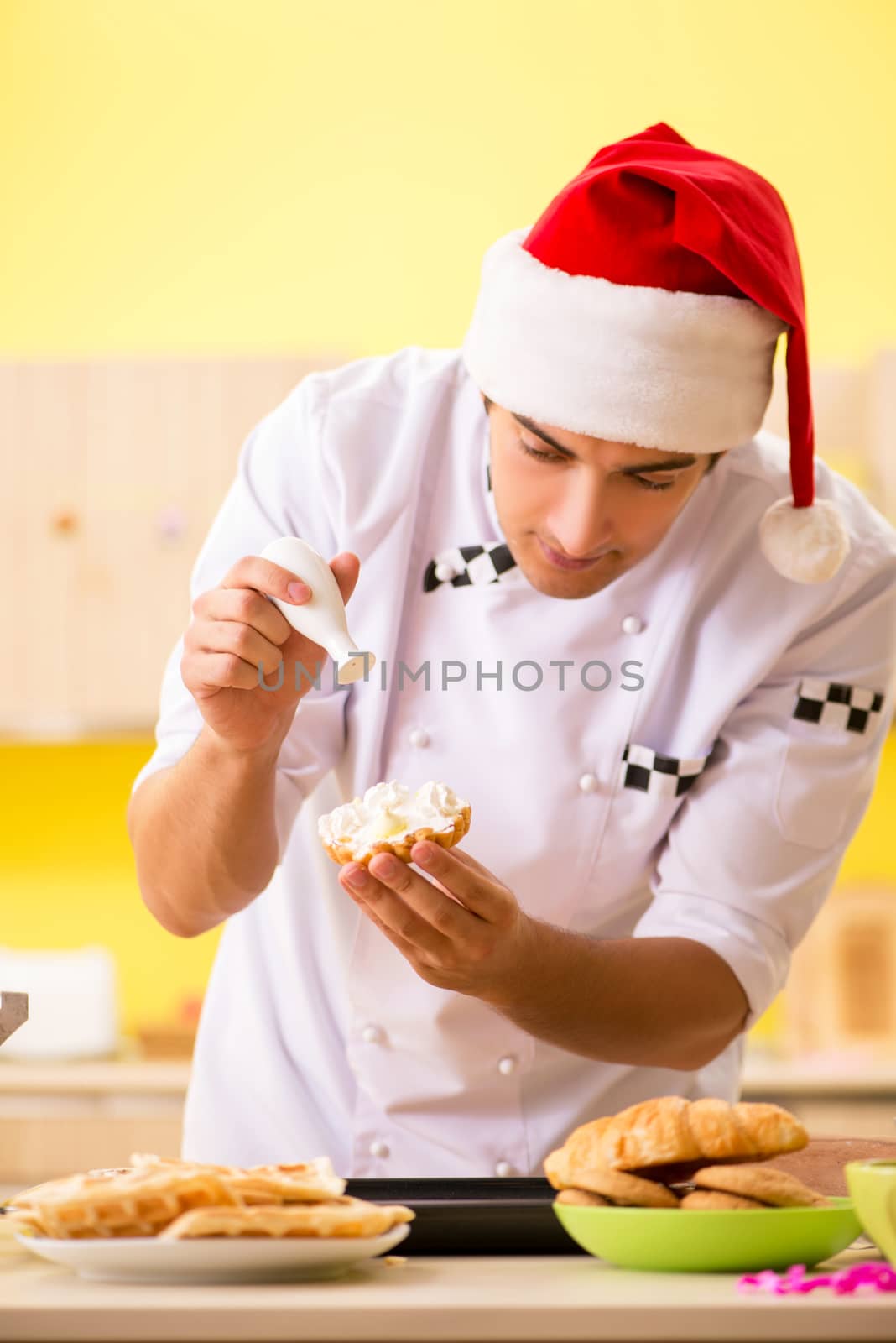 Young chef husband working in kitchen at Christmas eve  by Elnur