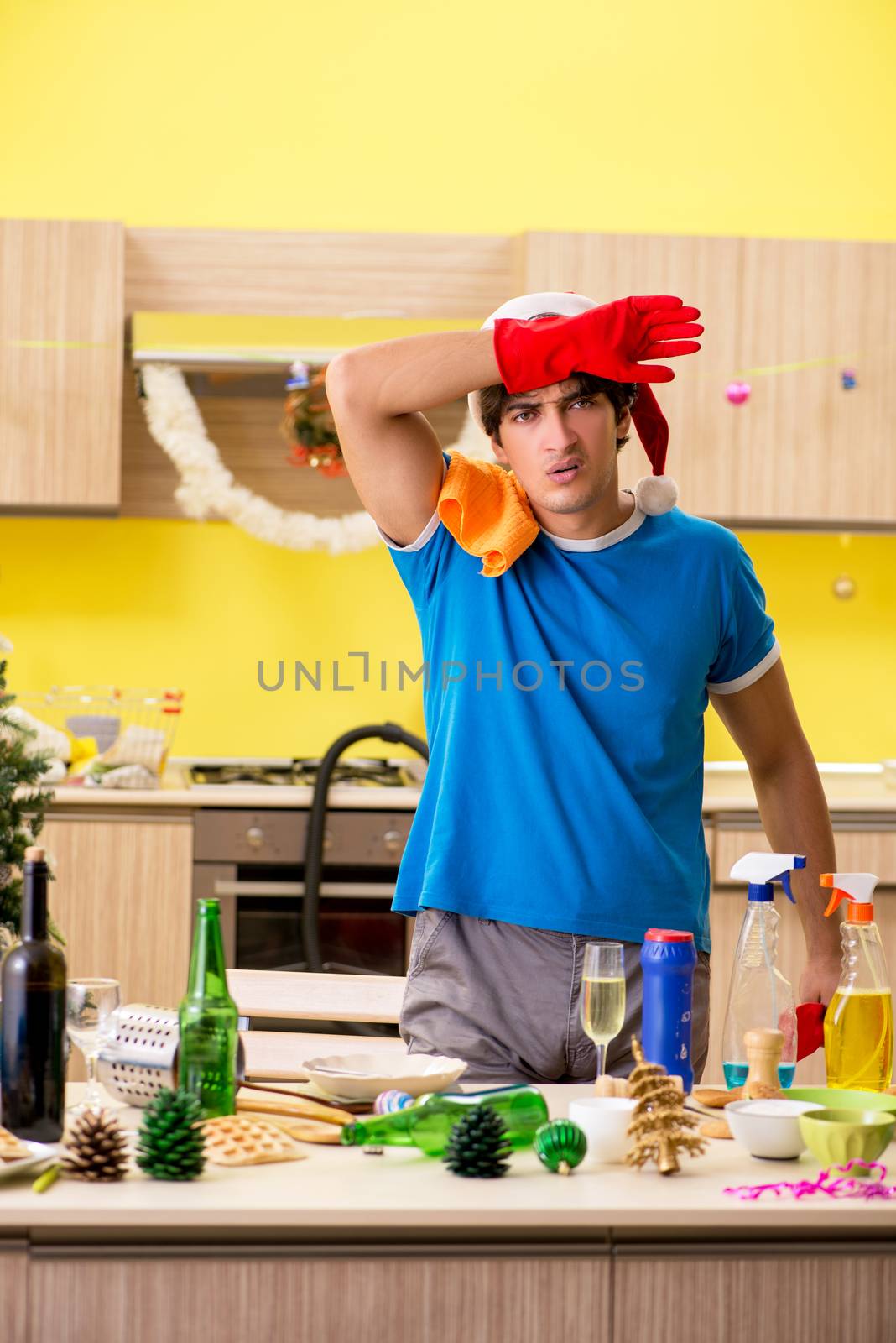 Young man cleaning kitchen after Christmas party 