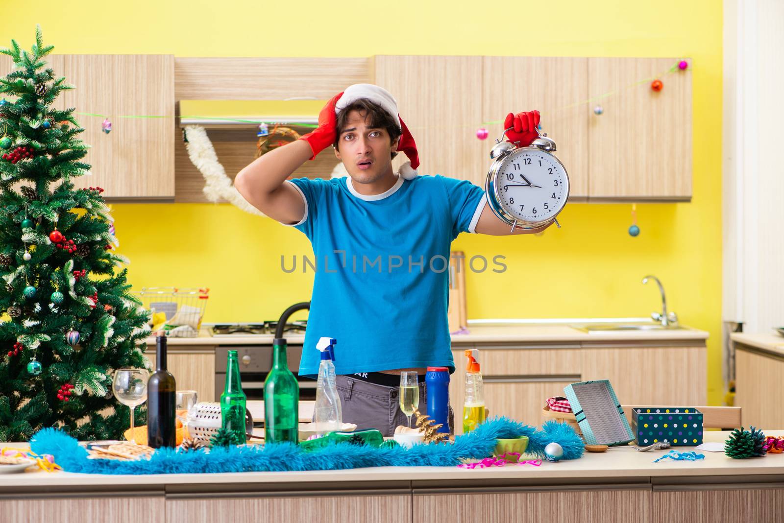 Young man cleaning kitchen after Christmas party 