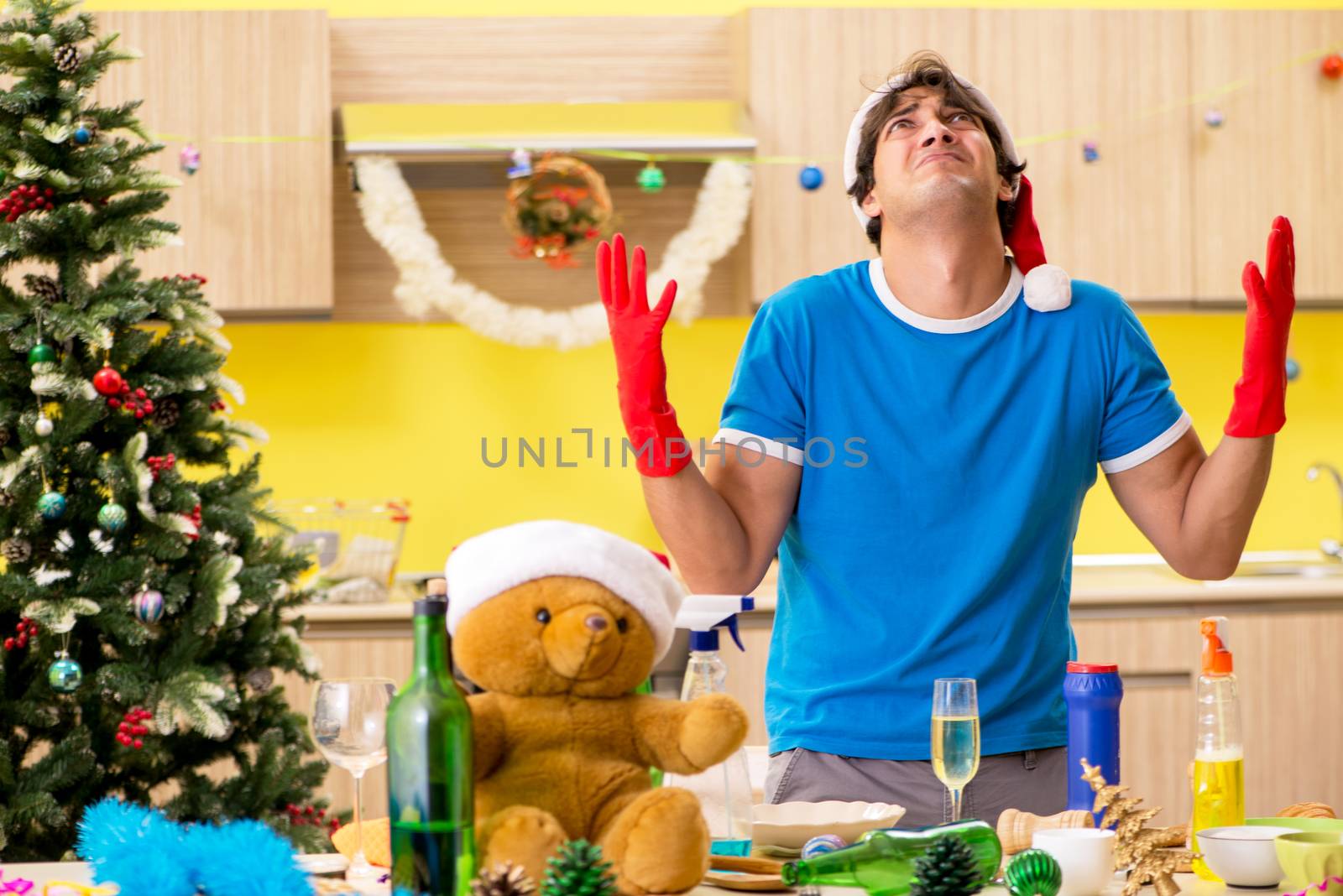 Young man cleaning kitchen after Christmas party 