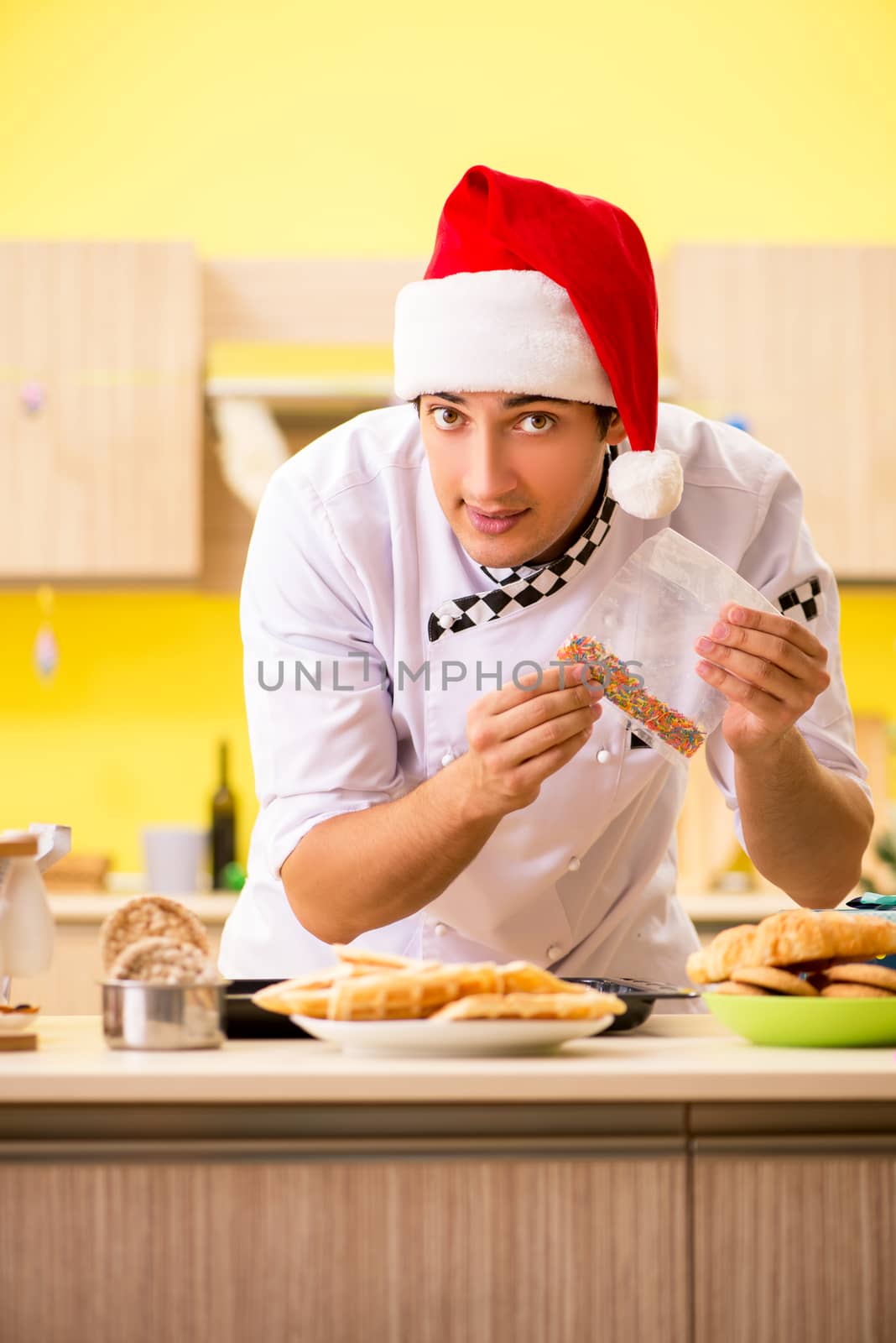 Young chef husband working in kitchen at Christmas eve  by Elnur
