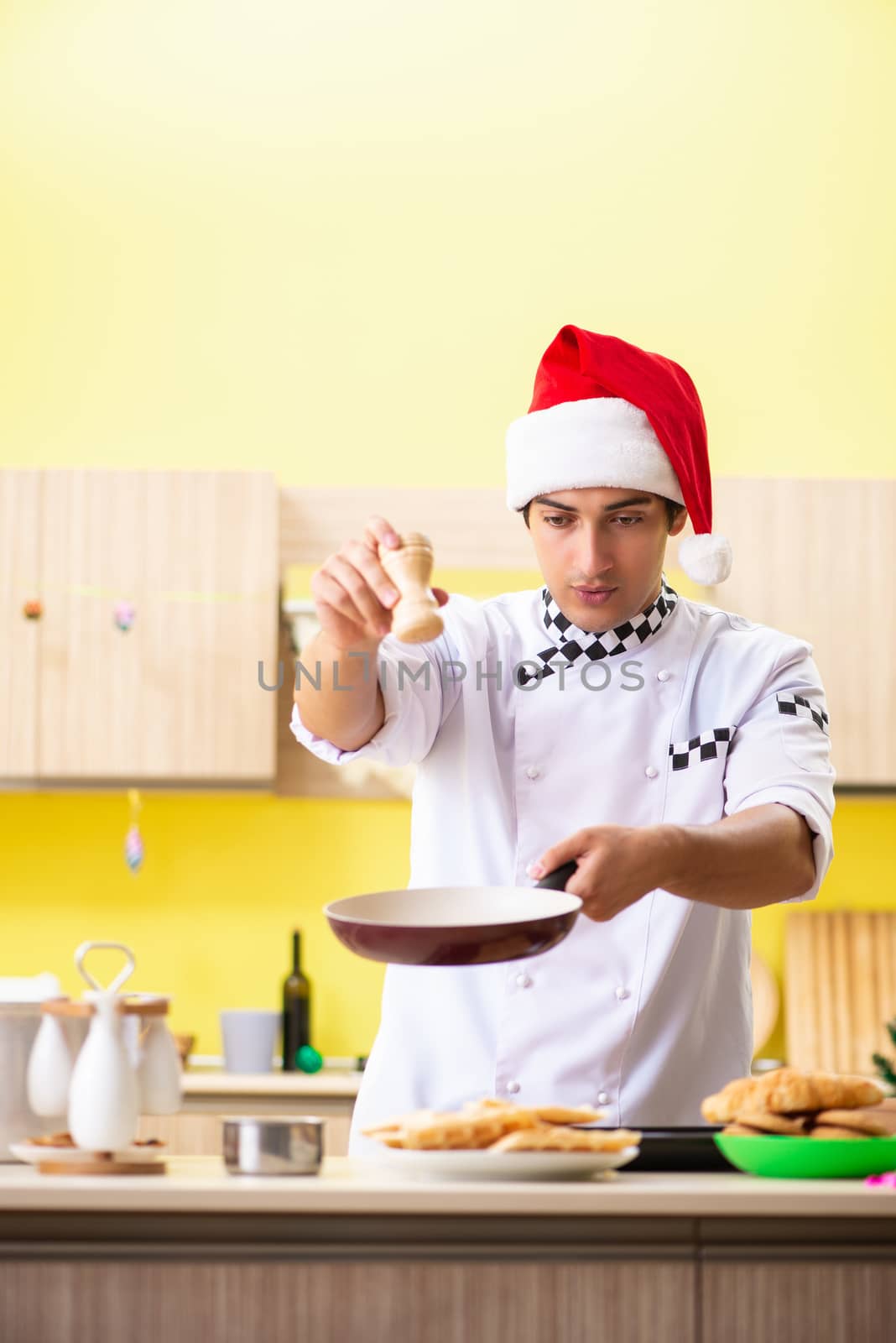 Young chef husband working in kitchen at Christmas eve  by Elnur