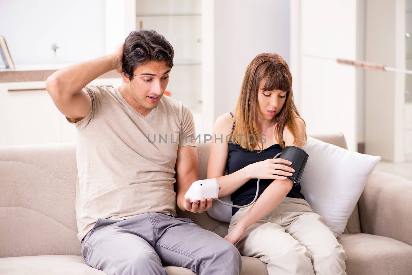 Husband checking wife's blood pressure