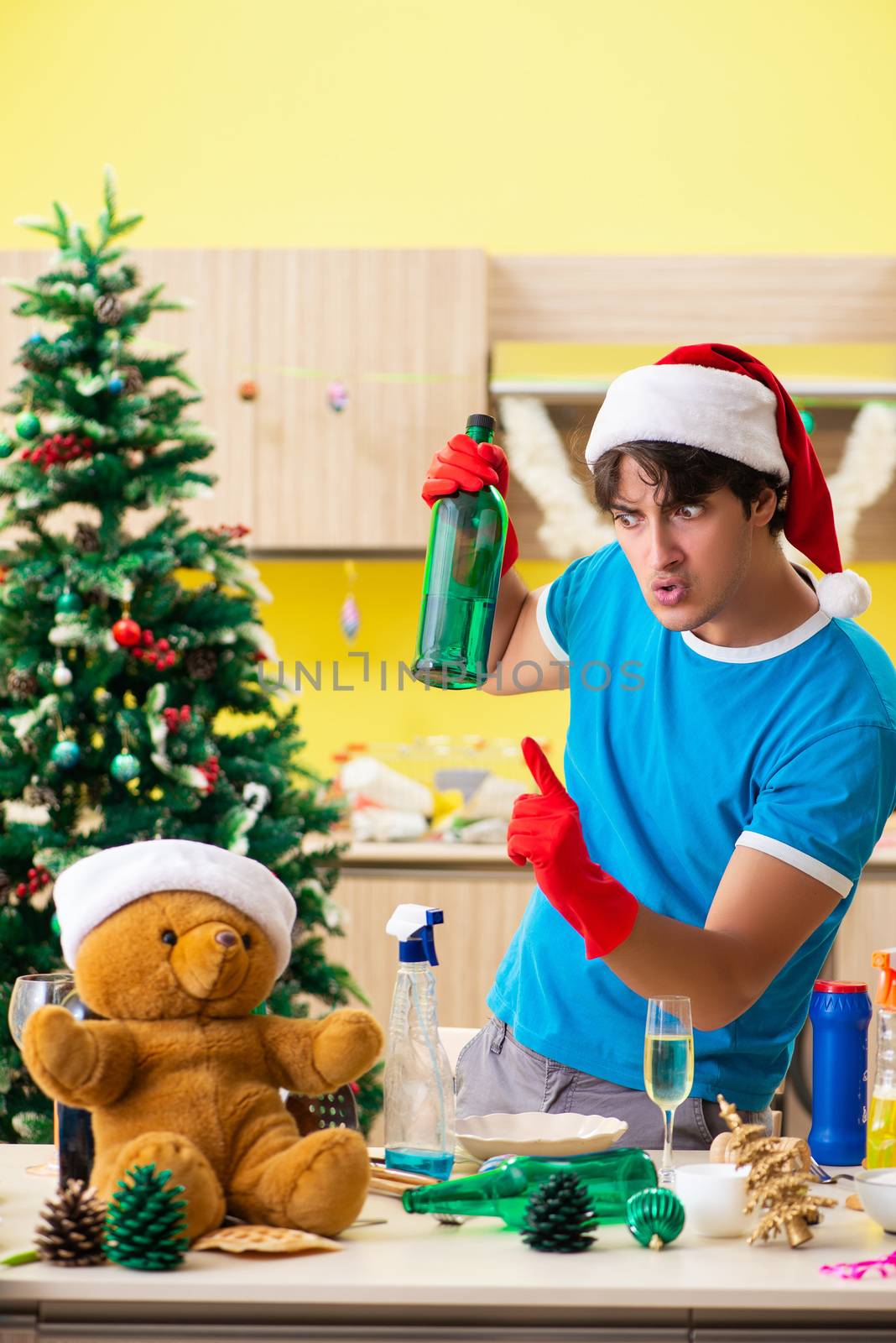 Young man cleaning kitchen after Christmas party  by Elnur