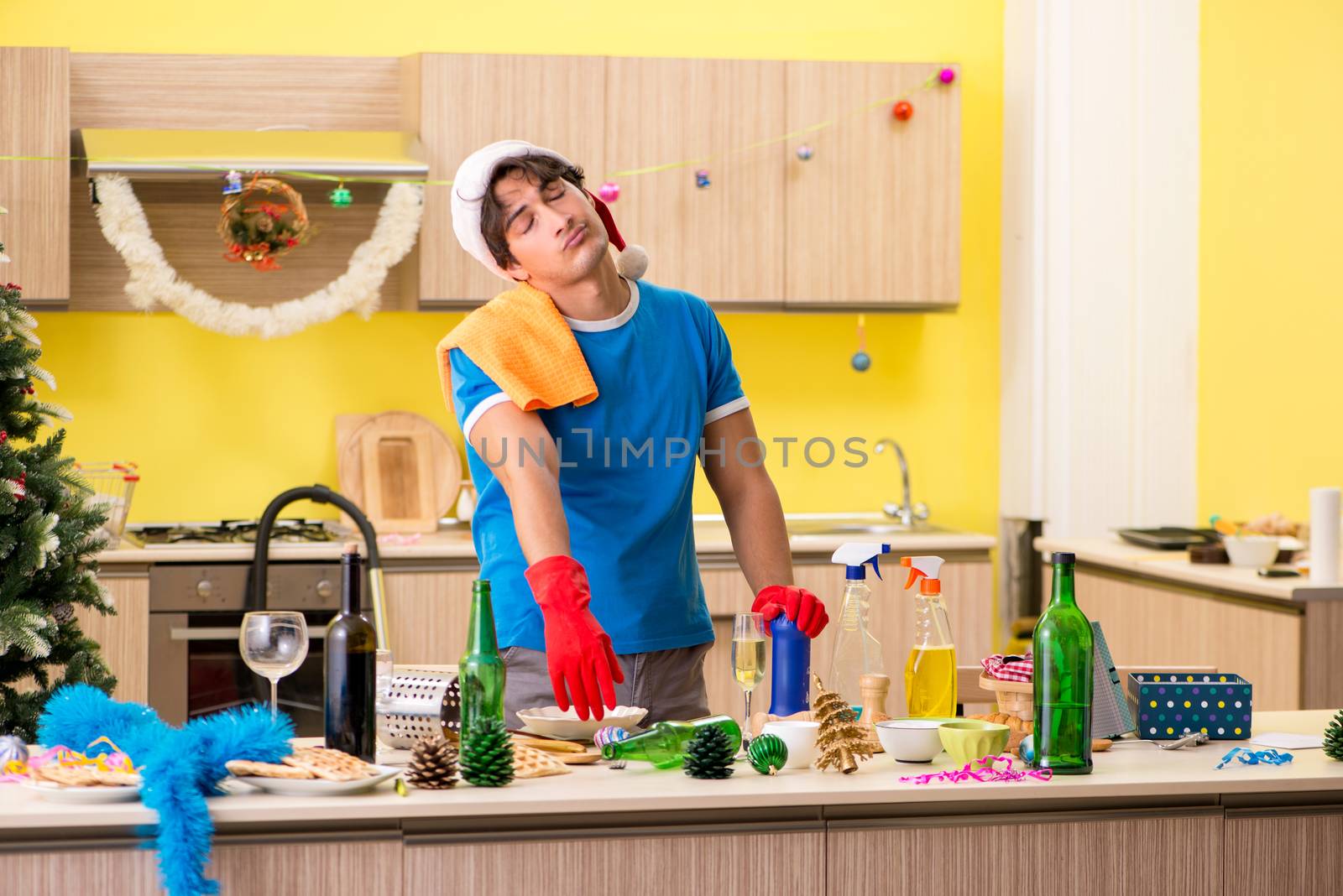 Young man cleaning kitchen after Christmas party 